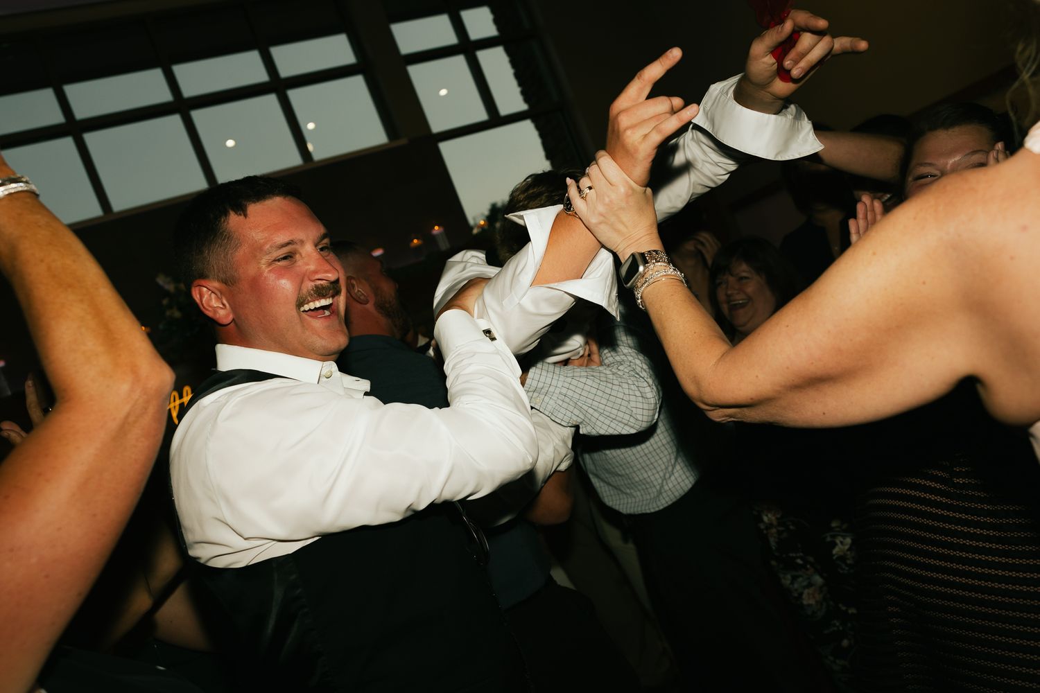 People dancing enthusiastically at a dimly lit indoor party.