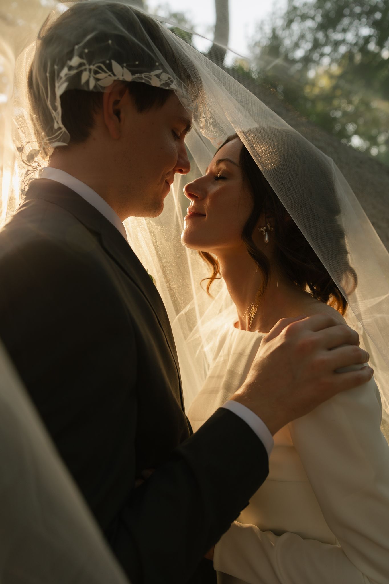 Backlit wedding portrait capturing an intimate moment between newlyweds.