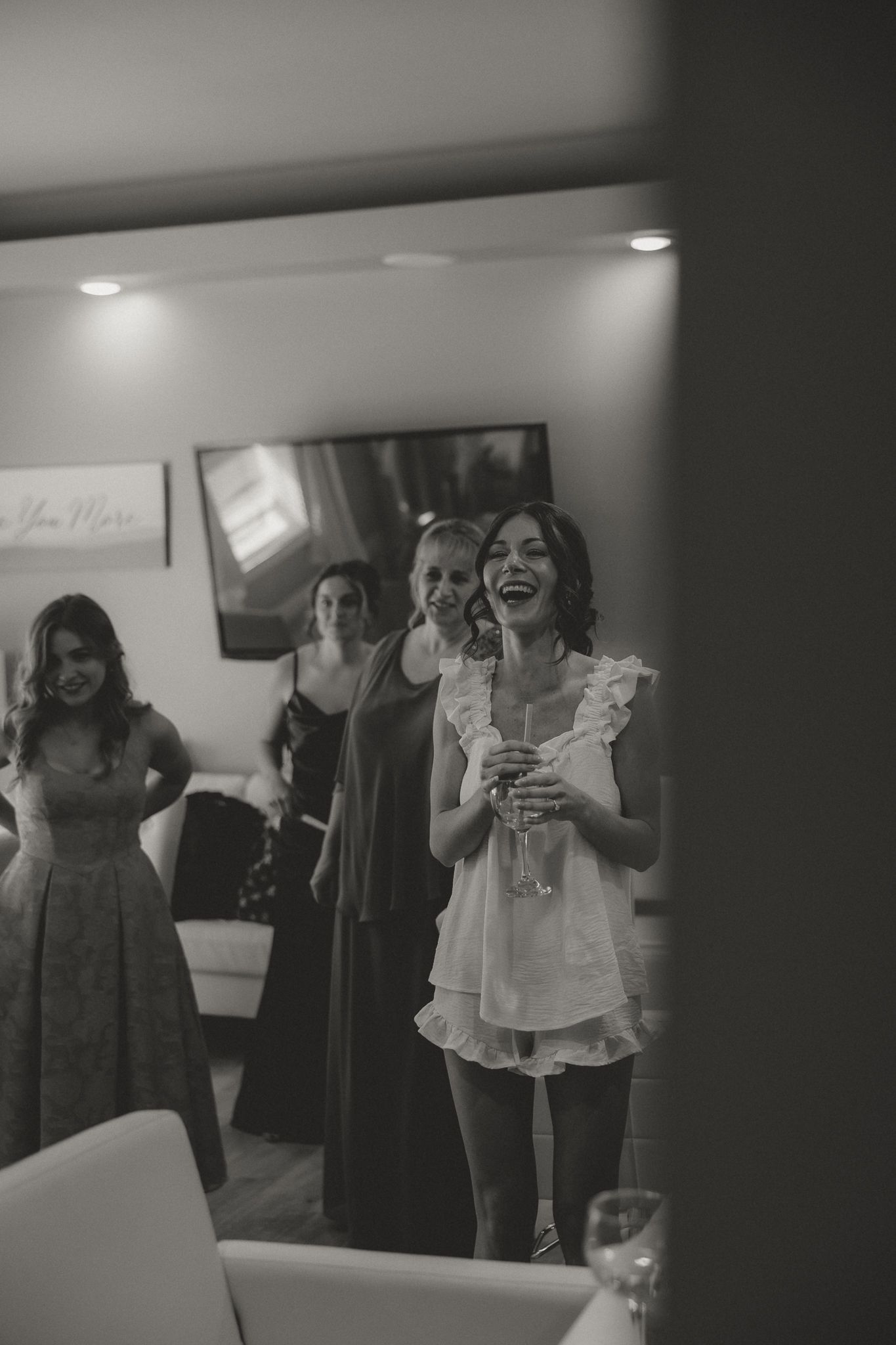 Wedding party members laugh and celebrate during a candid black and white moment at a reception.