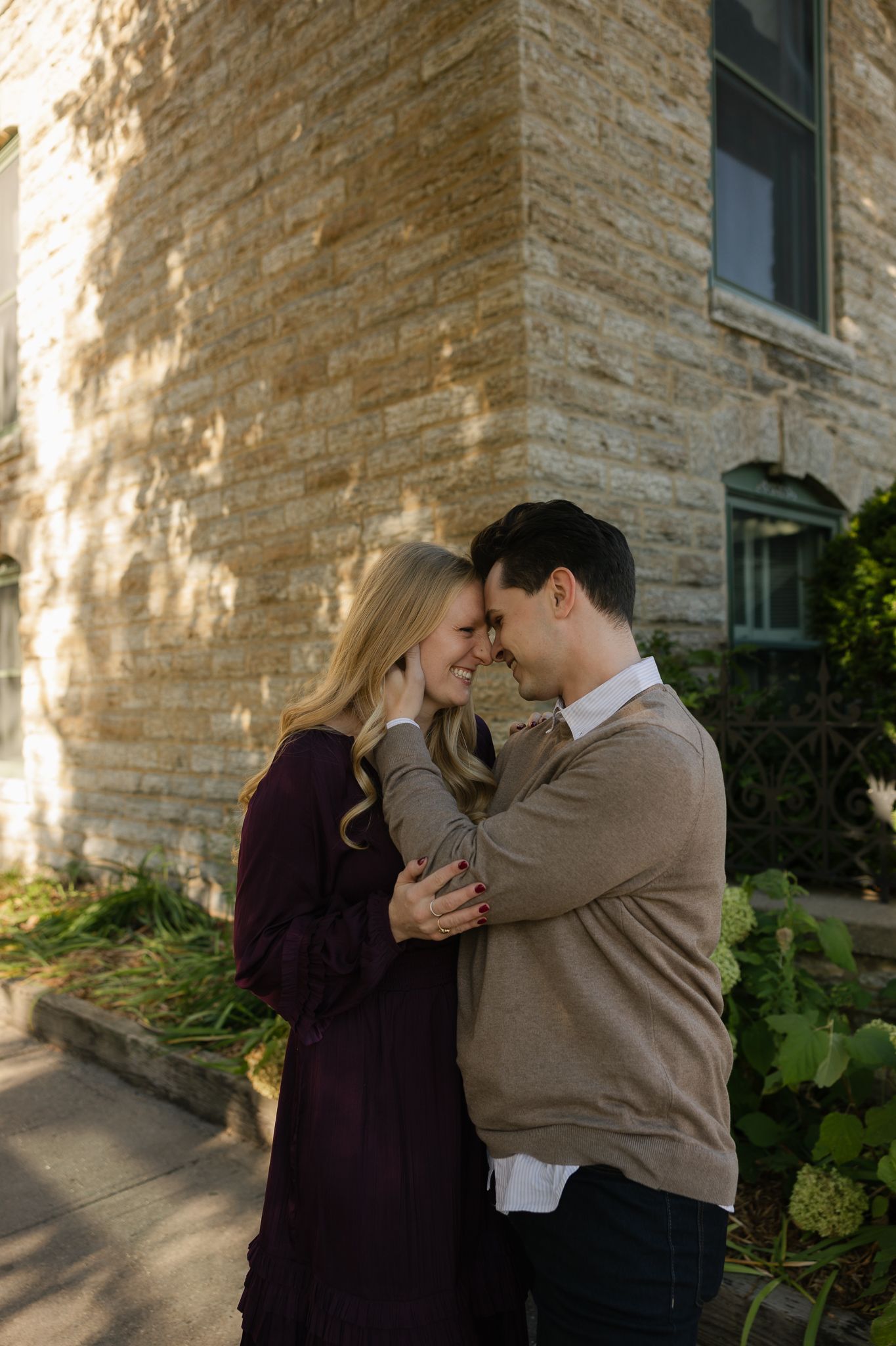 Intimate couple portraits captured against textured limestone building exterior.