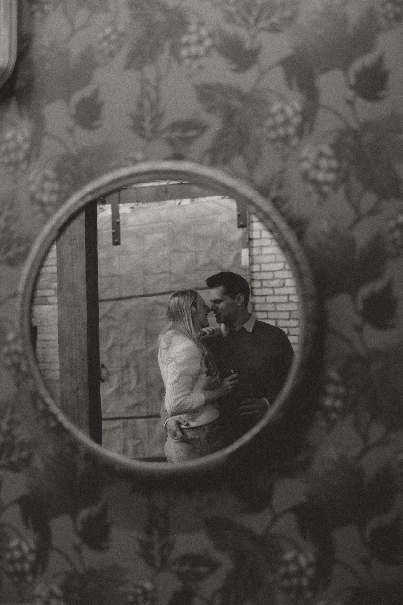 Reflection in vintage oval mirrors showing a romantic scene against floral wallpaper.