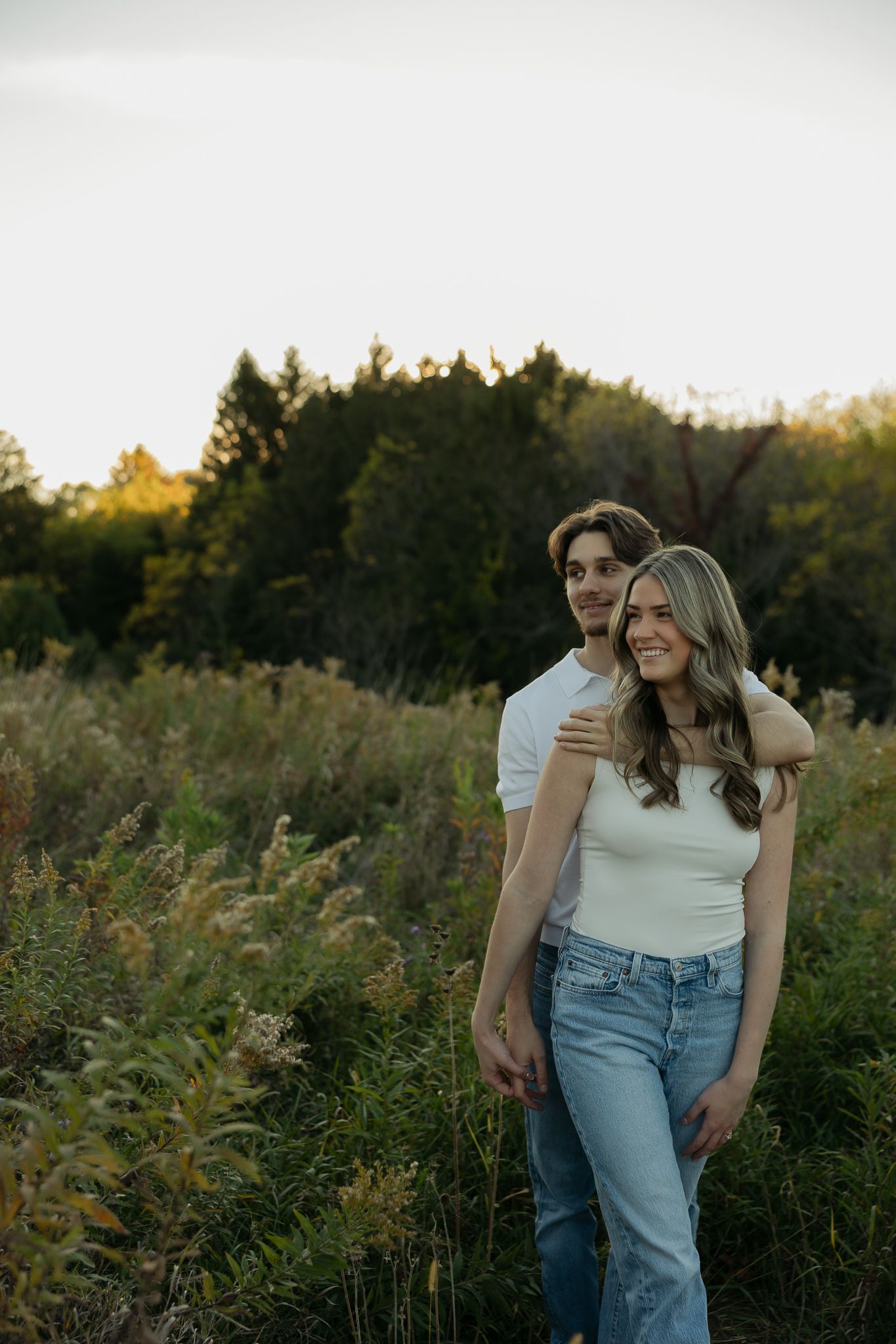 Couple in casual attire standing together in a wildflower field during golden hour.