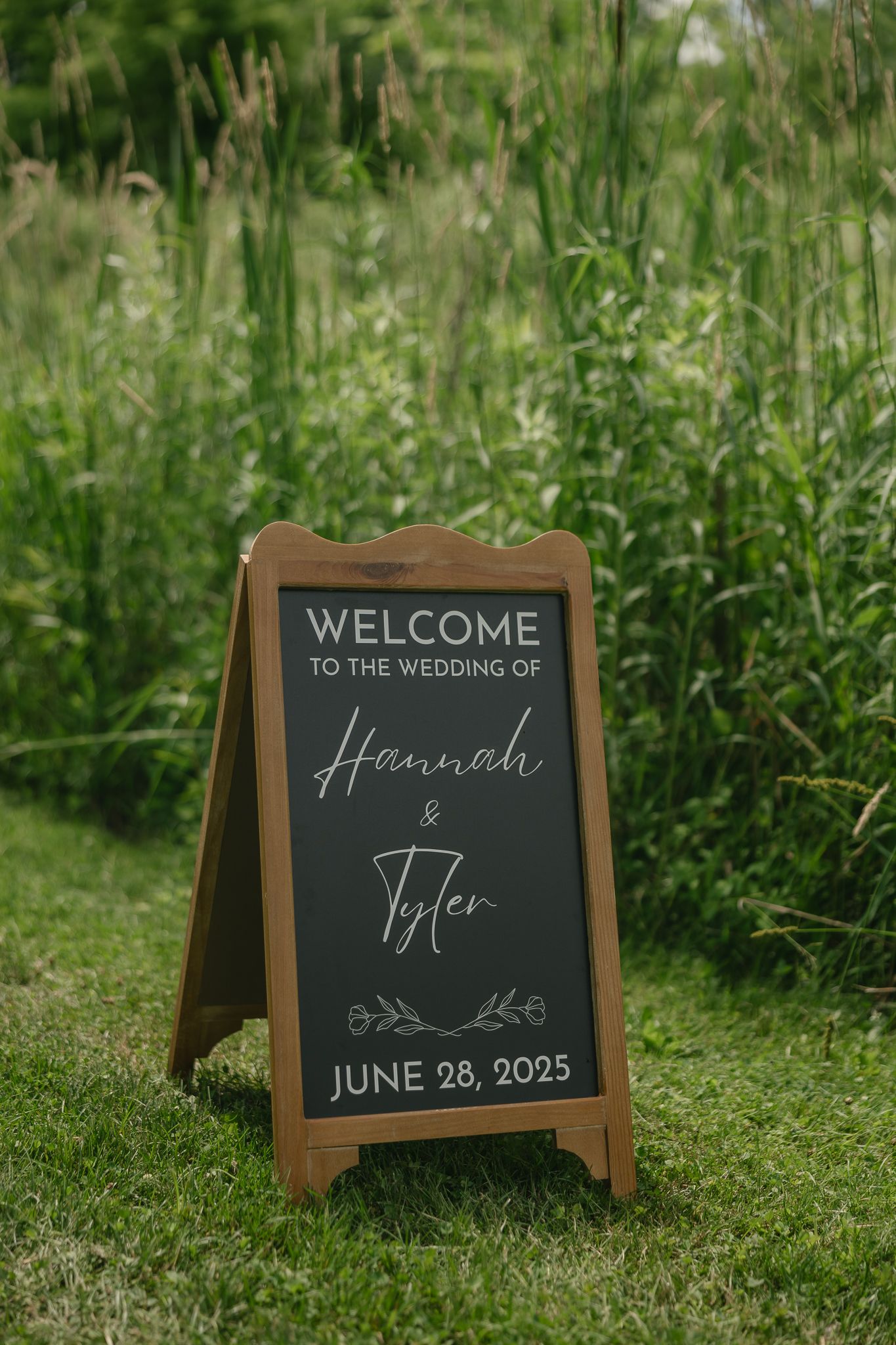 Rustic wooden welcome sign for a June wedding displayed on grass.