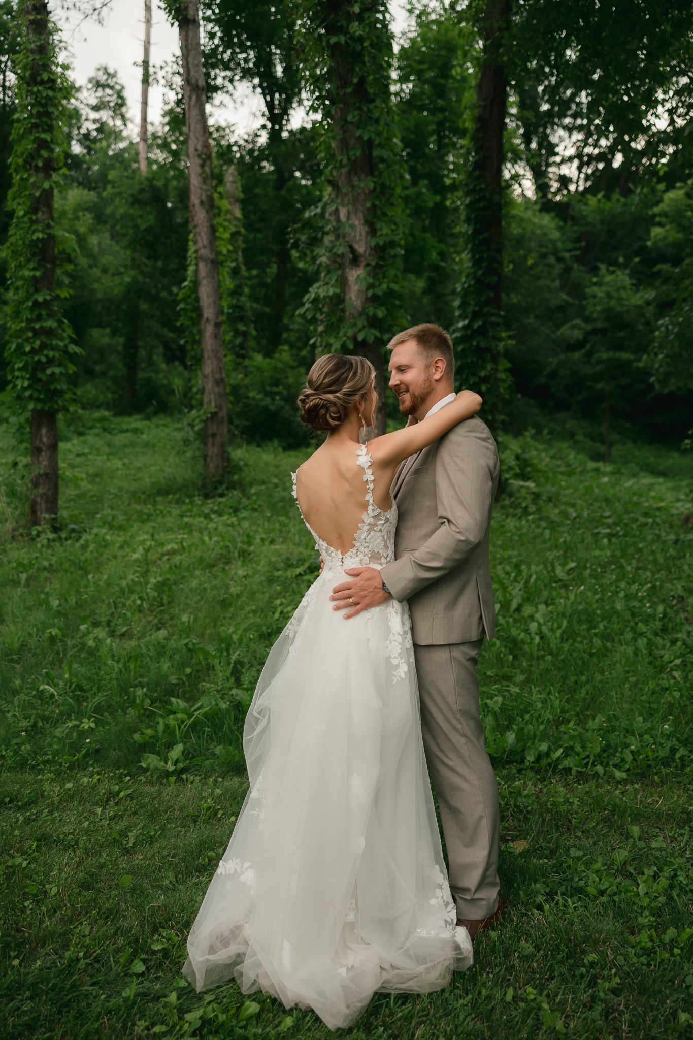Wedding couple shares a romantic dance in a verdant forest clearing.