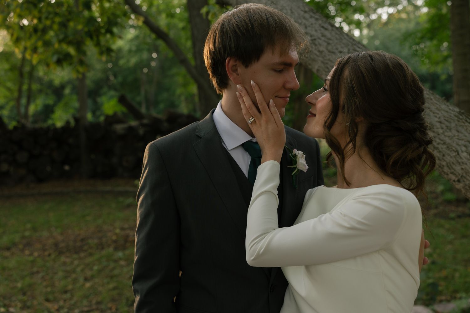 A romantic wedding couple shares a kiss in a garden setting.