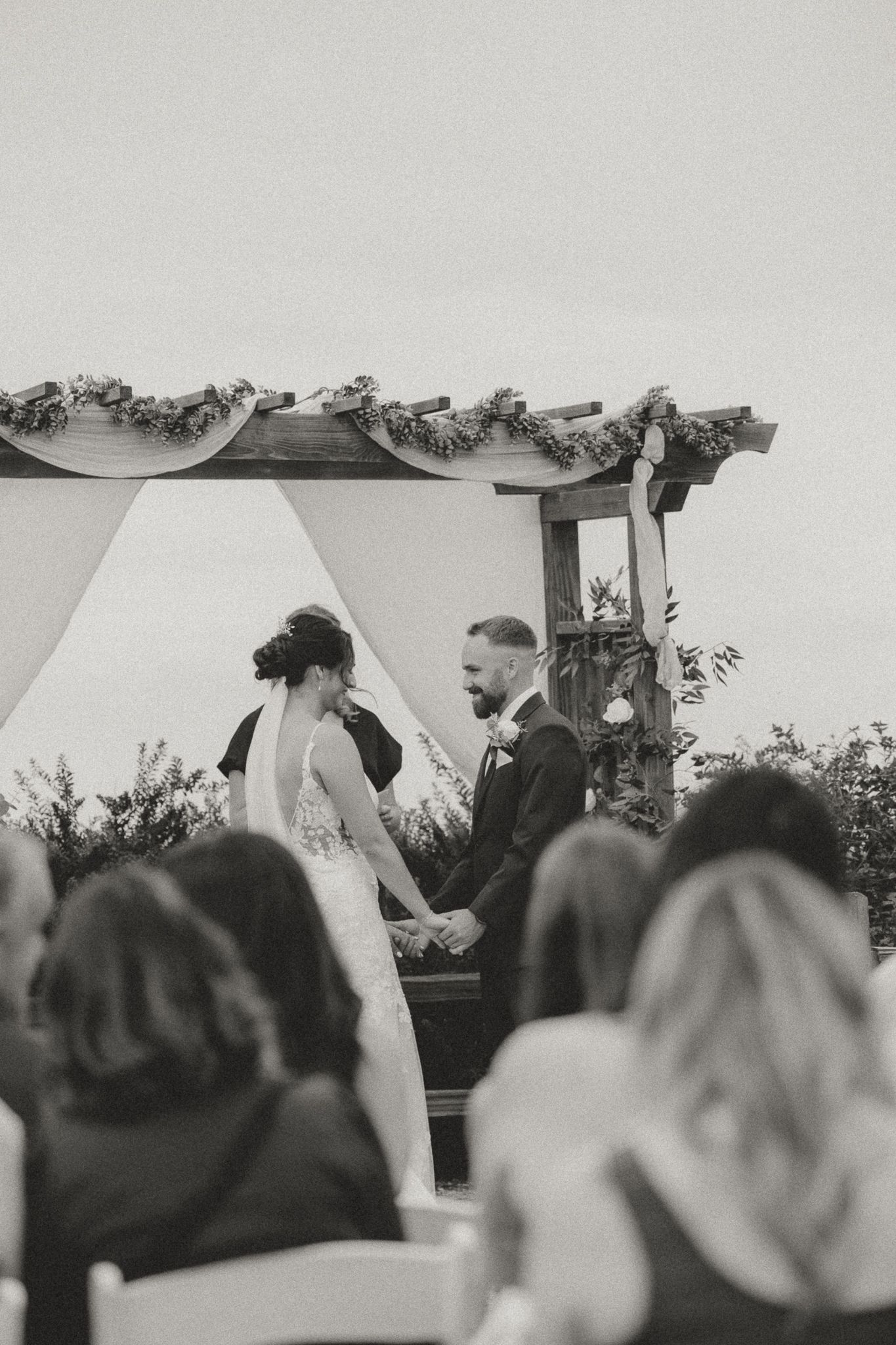 Black and white photo capturing intimate moments during outdoor wedding ceremony.