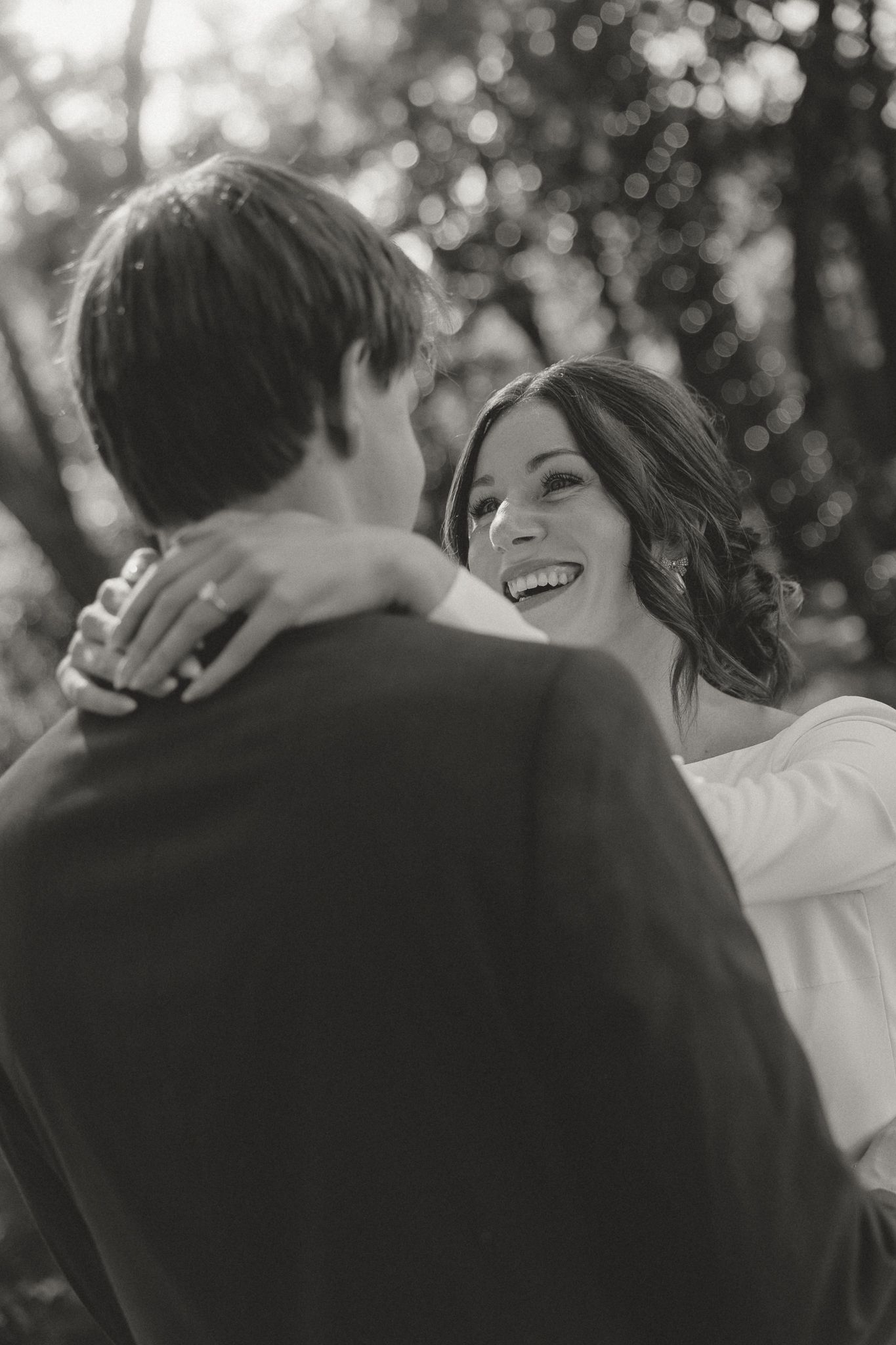 A romantic black and white outdoor photo showing a couple embracing and laughing together.