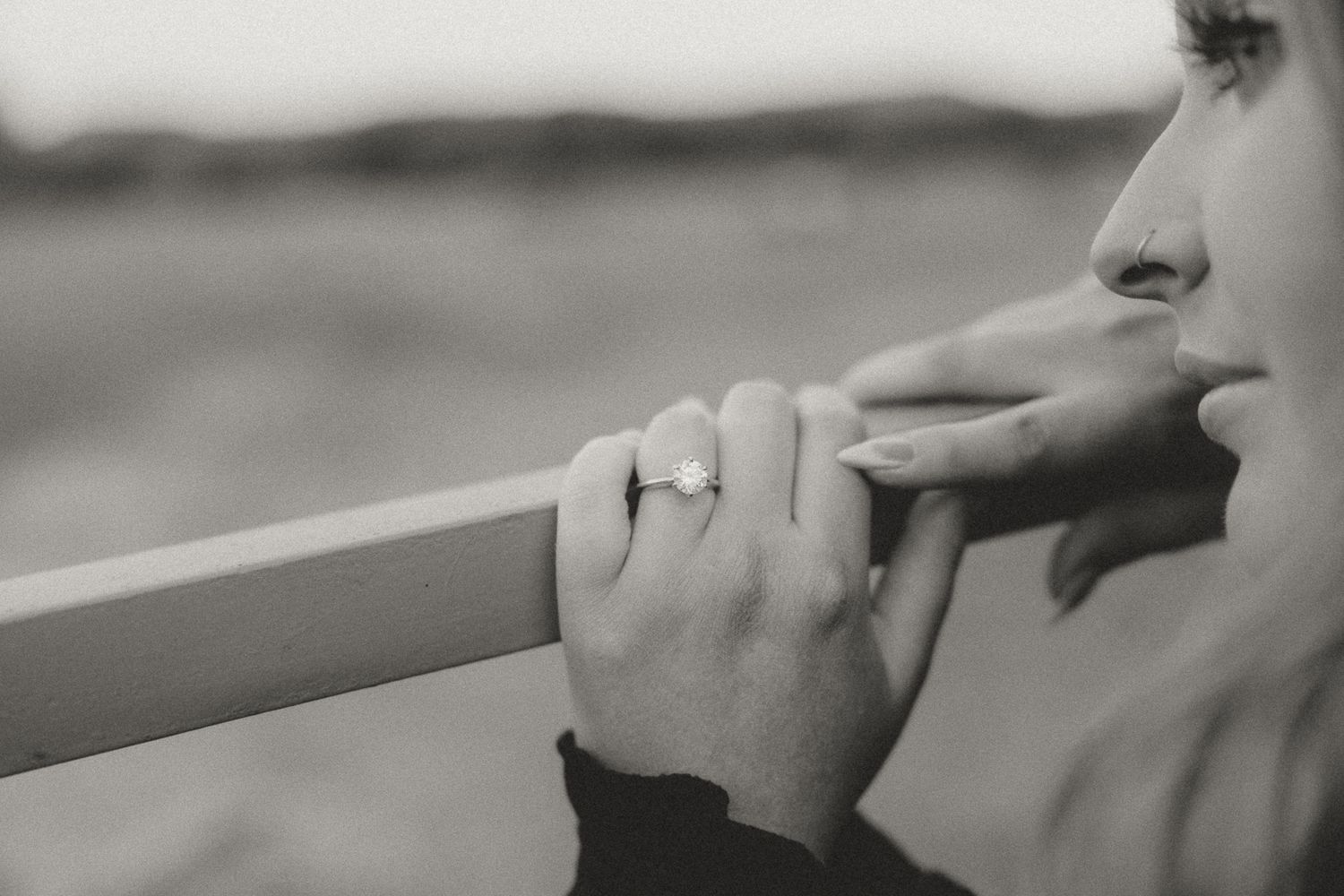 A close-up black and white photo showing hands and profile against a railing.