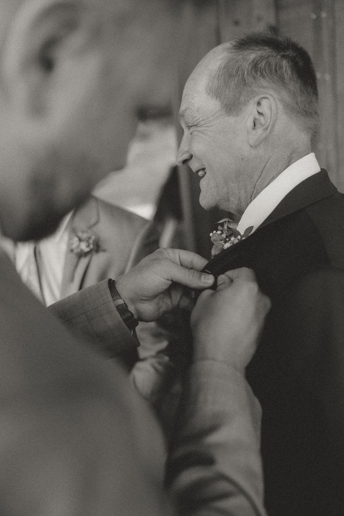 Black and white photo of groomsmen adjusting their boutonnieres before the ceremony.