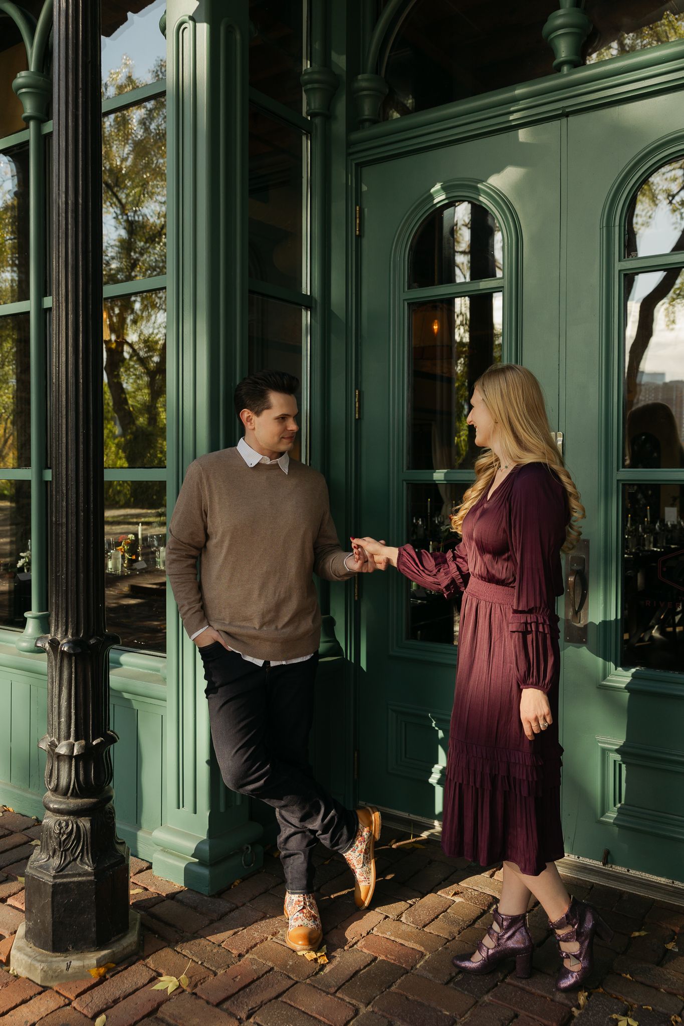 A couple sharing a romantic moment outside a green-painted building entrance.