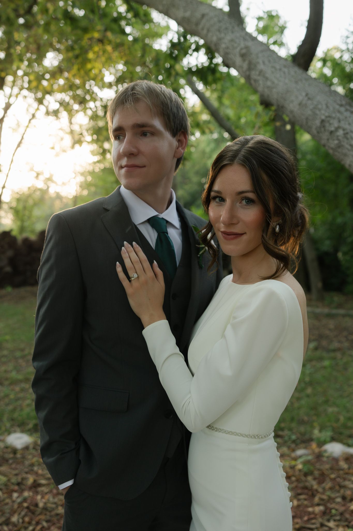 A couple shares playful moments during their wedding photoshoot in a wooded setting.