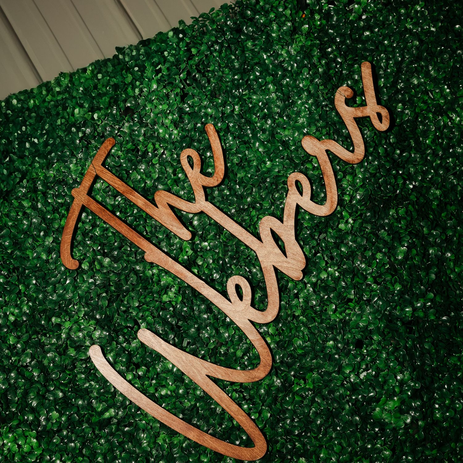Decorative wooden 'Love' text sign against green foliage backdrop.