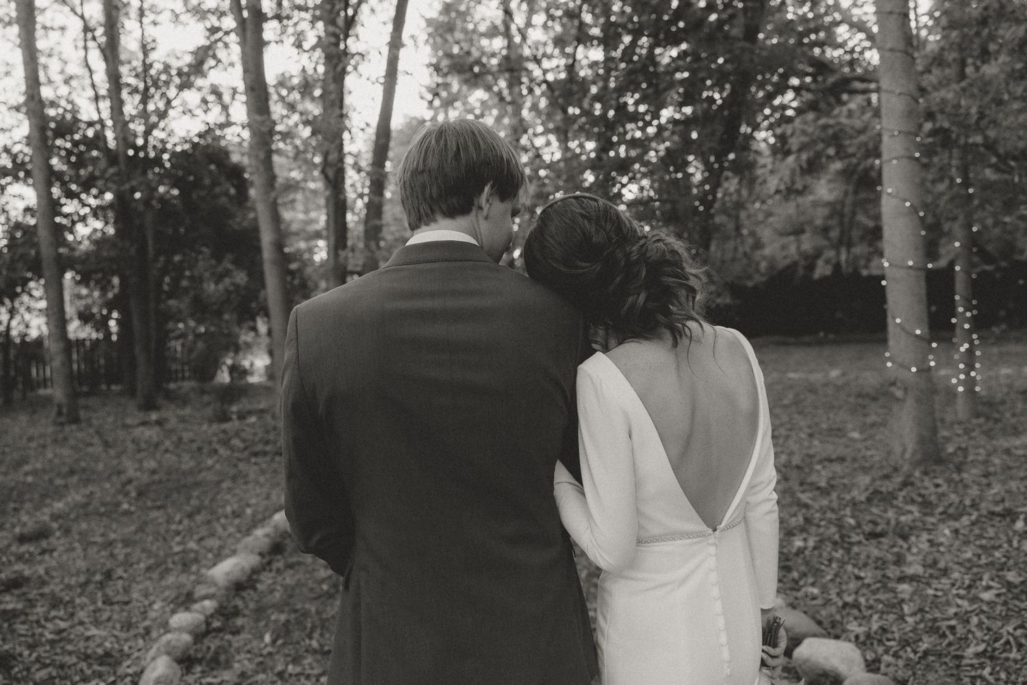 A couple walks together through a scenic wooded area on their wedding day.