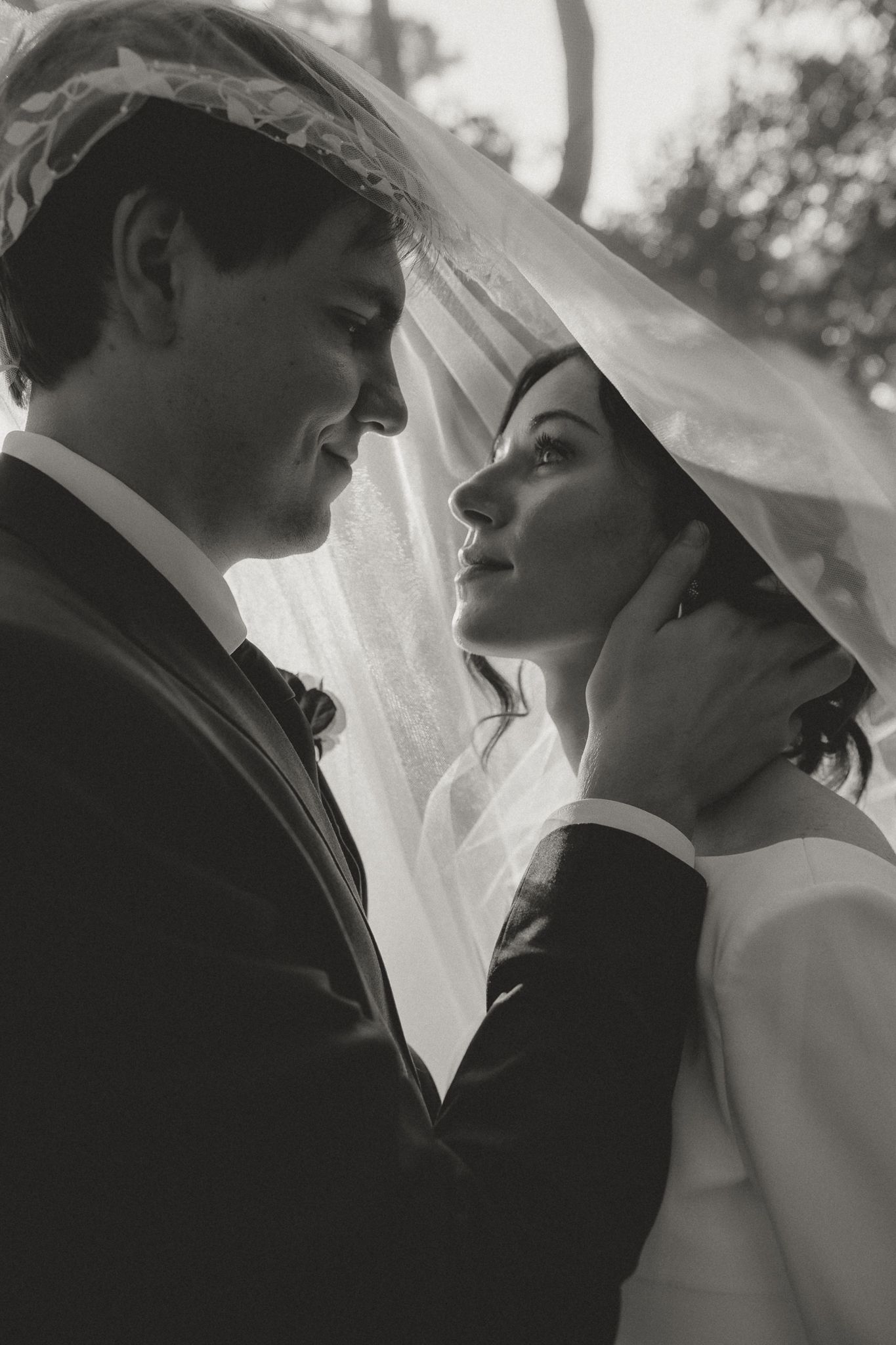 Black and white romantic portrait of a couple in wedding attire sharing an intimate moment.