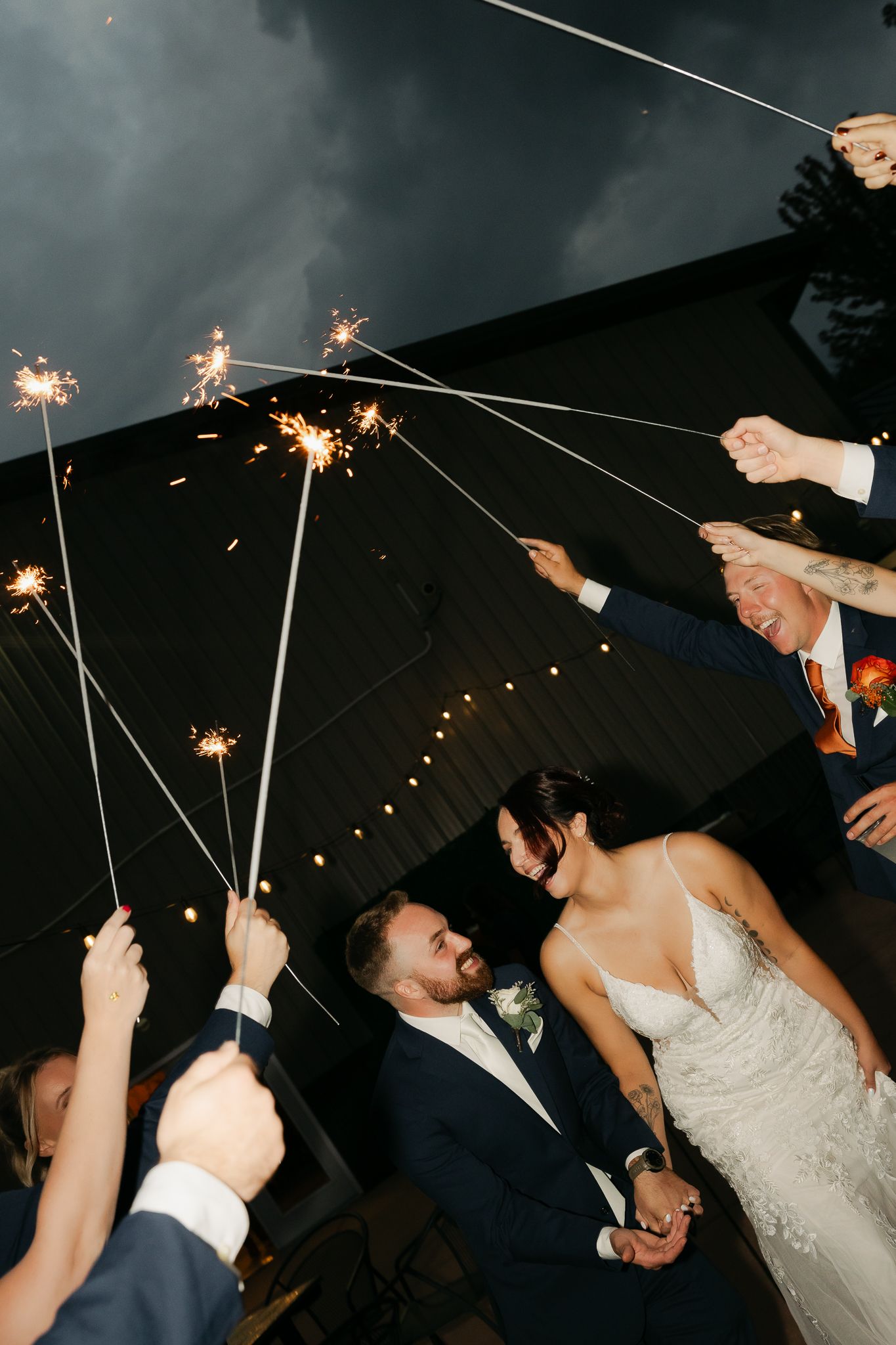 Wedding celebration with sparklers creating a magical archway at night.