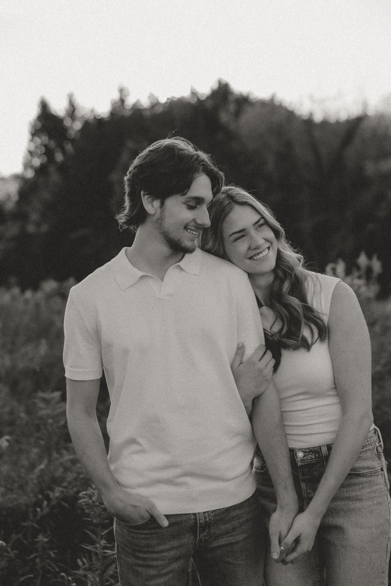 Black and white portrait of couple laughing together in casual outfits.