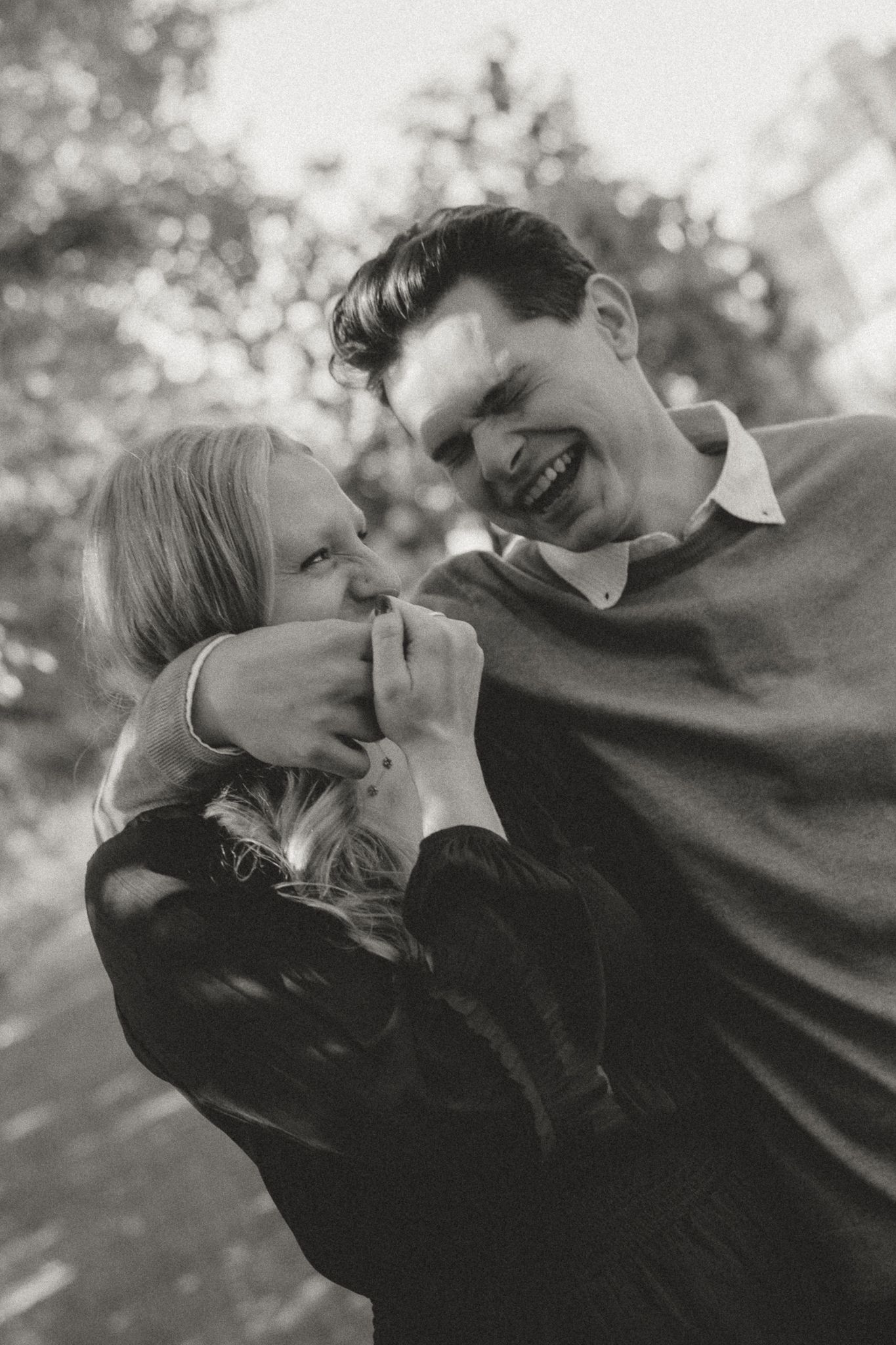 Candid black and white photo capturing a joyful moment between two people outdoors.
