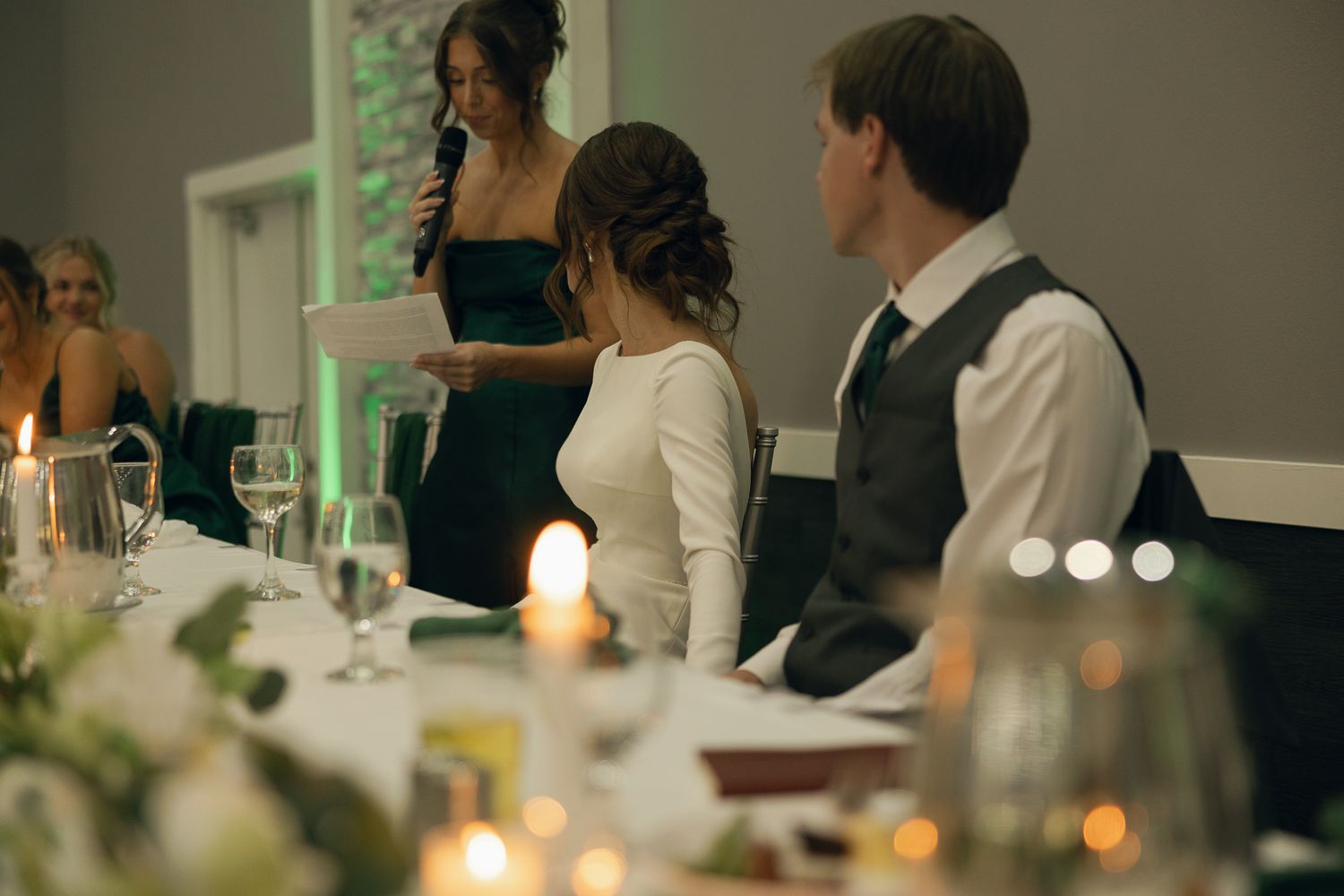 Wedding reception scene with candlelit tables and guests gathered for celebration.