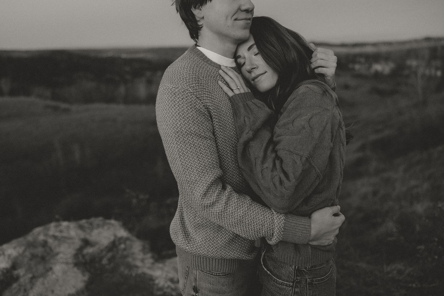 Romantic couple embracing outdoors in black and white photography.
