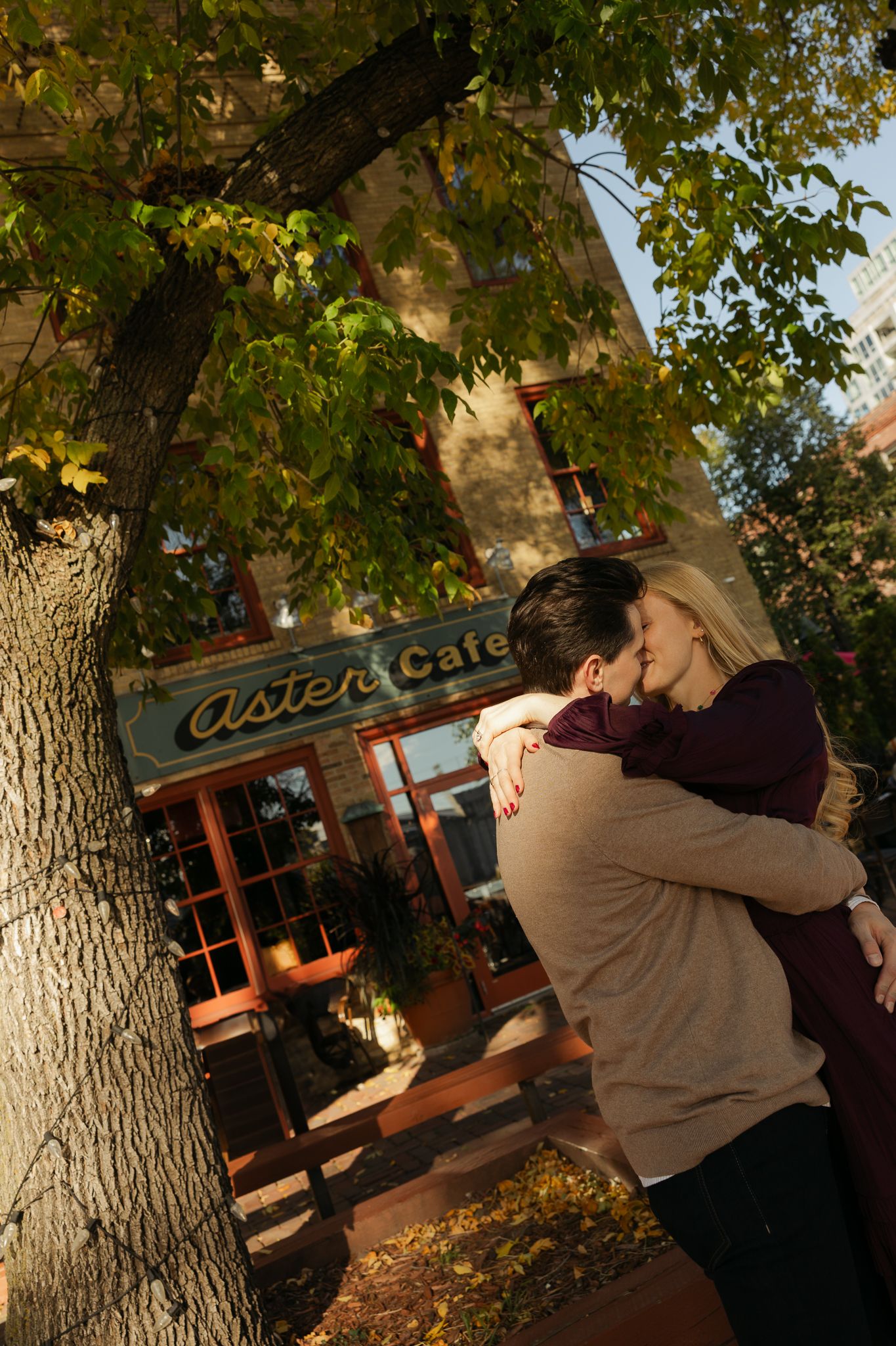 Romantic autumn scene outside Oyster Bar with couple embracing under golden leaves.