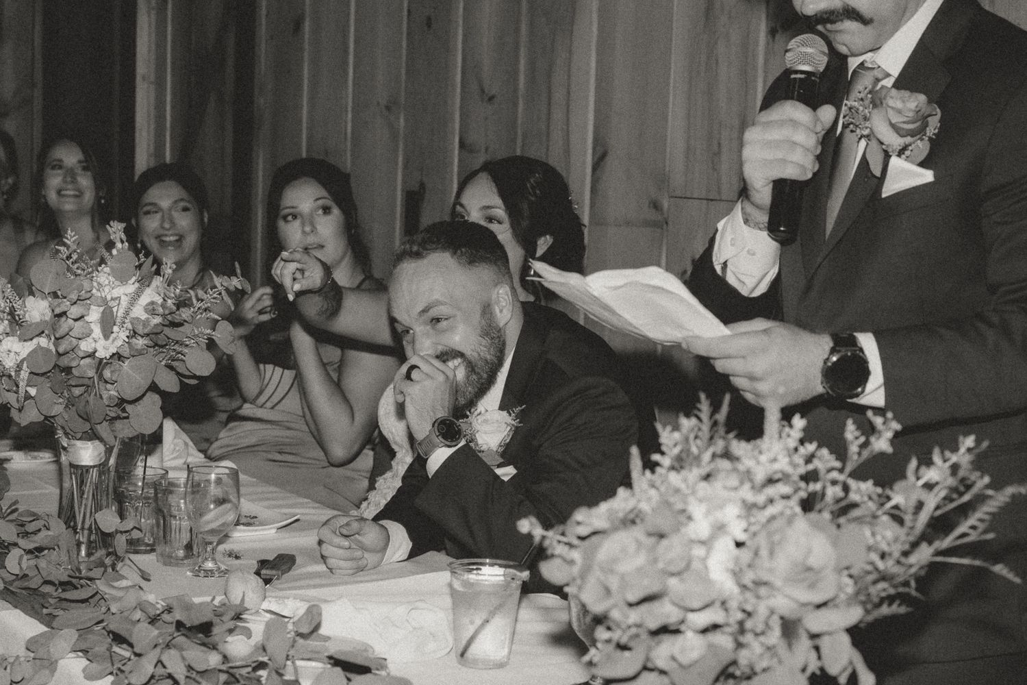 Vintage style black and white photo of wedding guests enjoying a lively reception dinner.