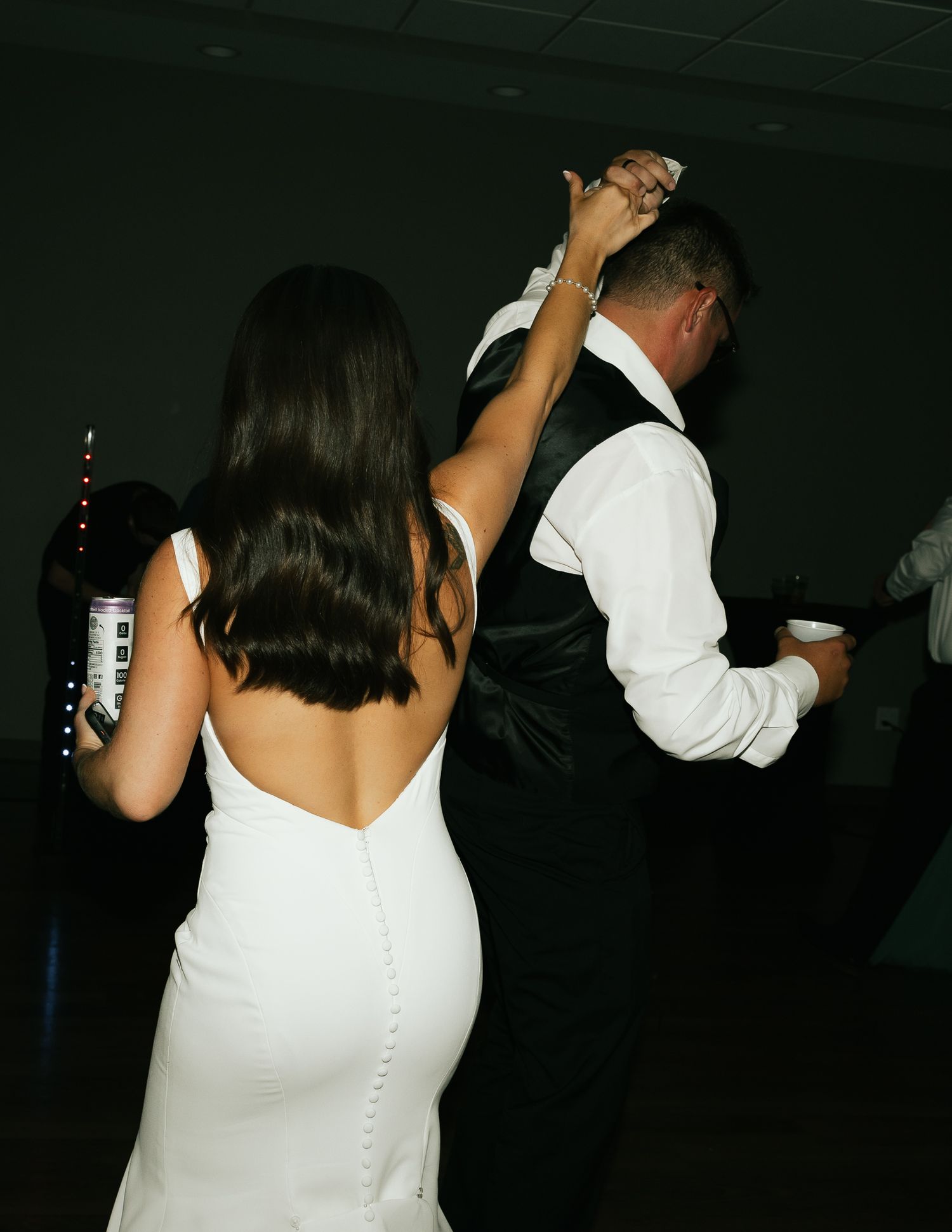 A bride in a white dress dances with guests at her wedding reception.