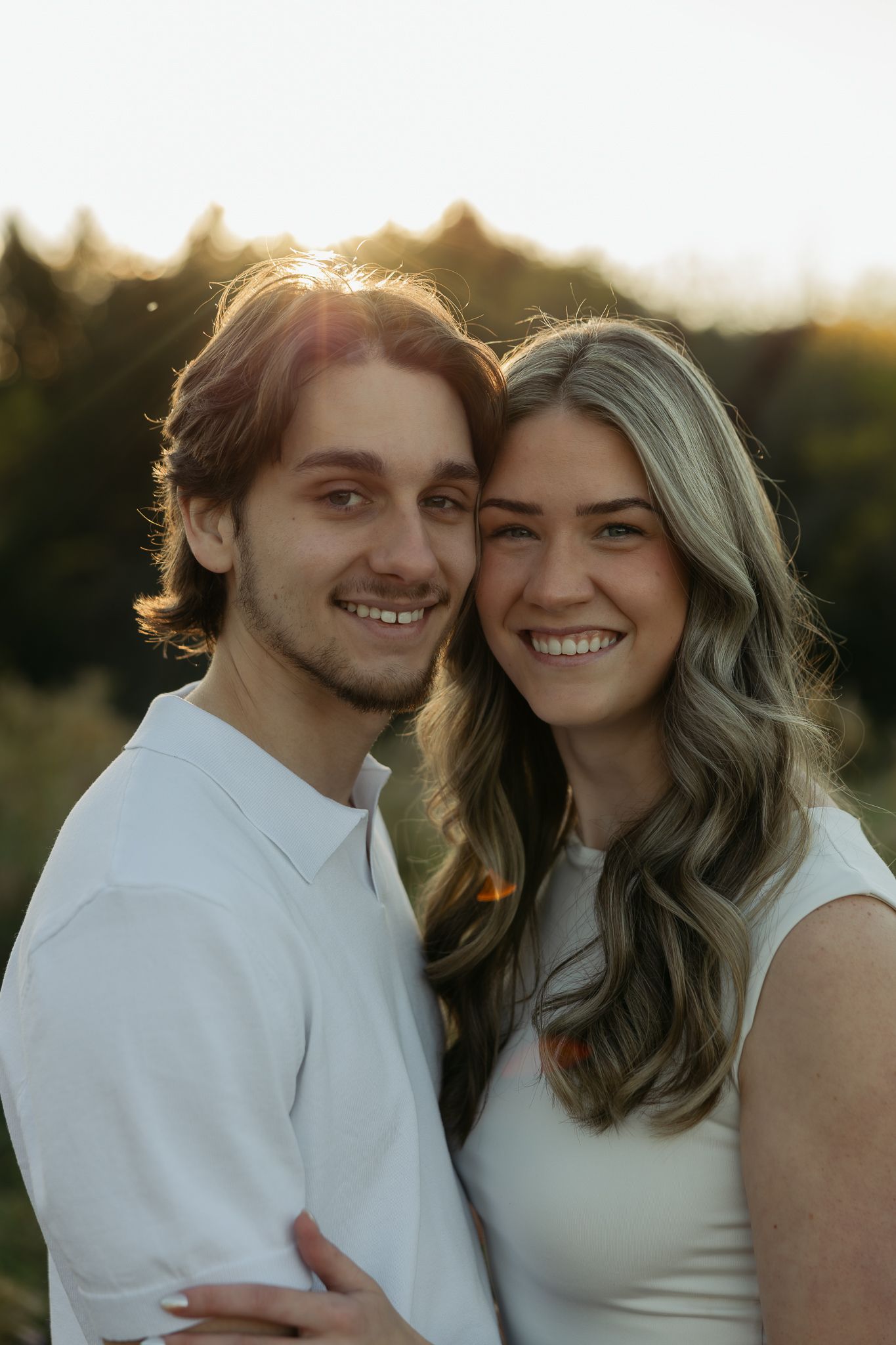 Couple in white outfits share intimate moment during golden hour photoshoot.