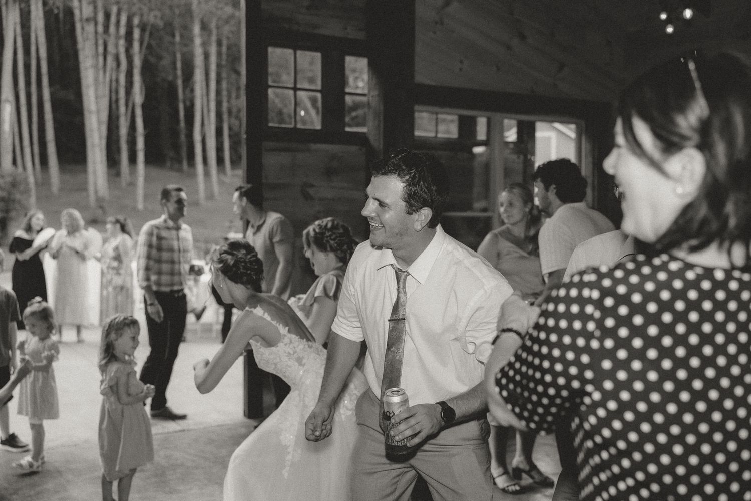 Wedding reception dance party in a rustic venue with guests enjoying the celebration.