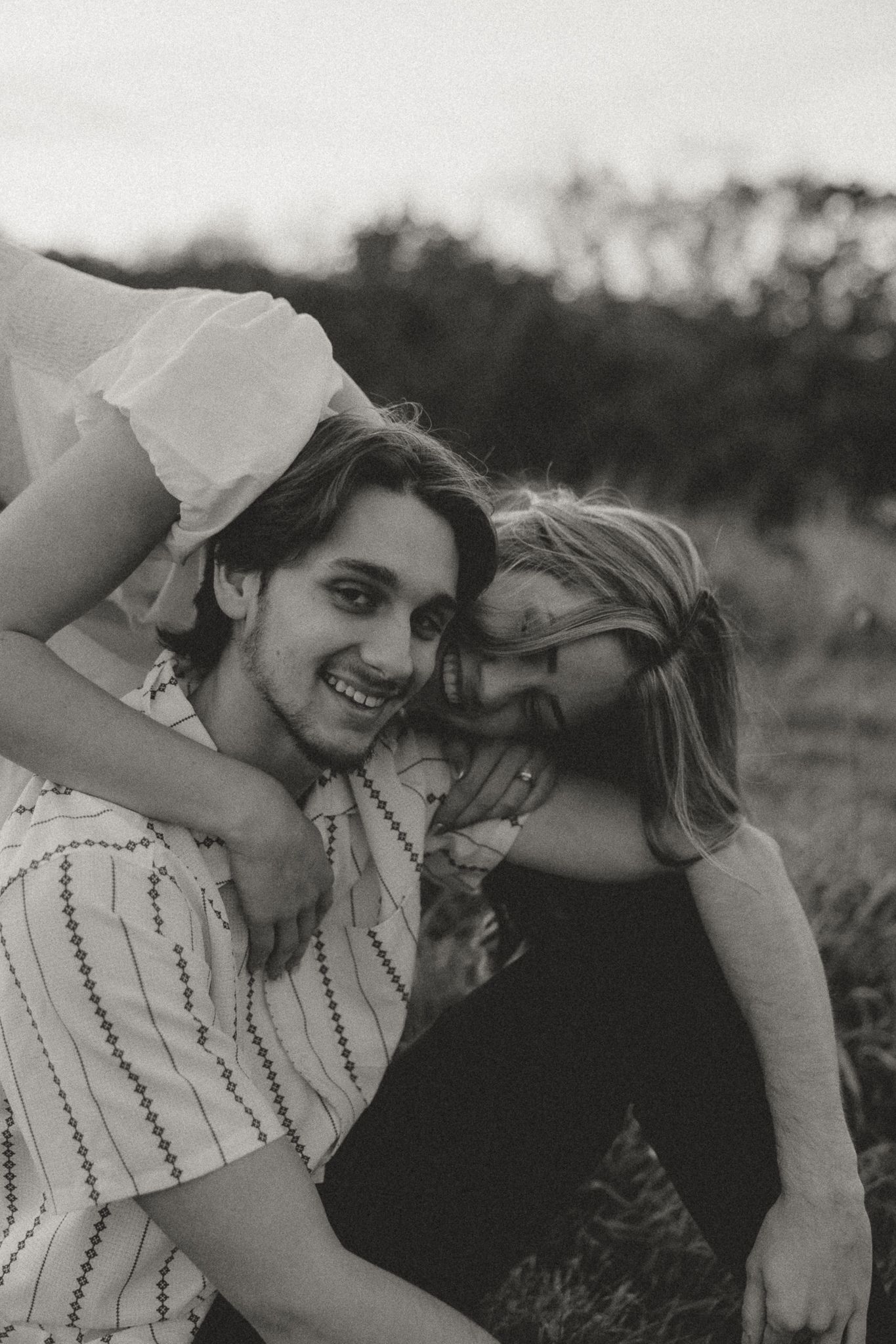 Black and white photo of couple sharing affectionate moments outdoors.