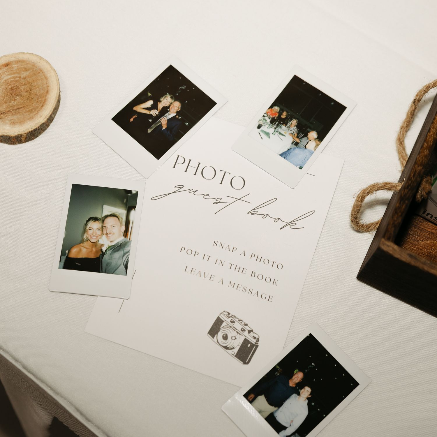Wedding guest book table with scattered polaroid photos and signature spaces.