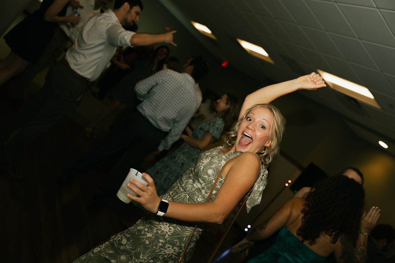 Guest dancing and celebrating at a dimly lit indoor reception.