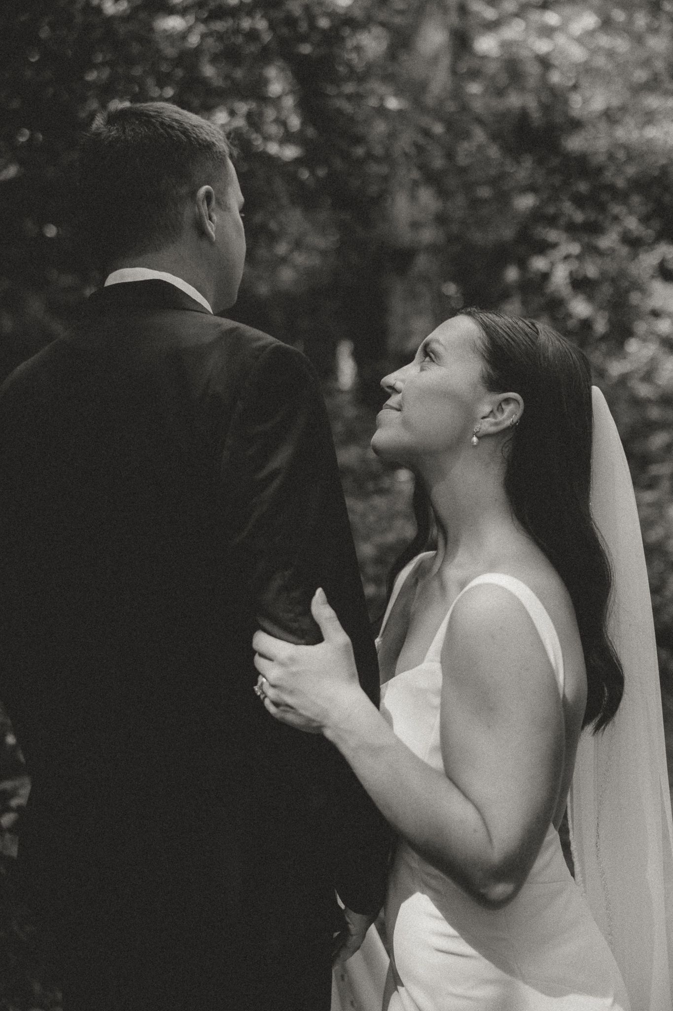 Artistic black and white wedding portrait capturing an intimate moment in the woods.