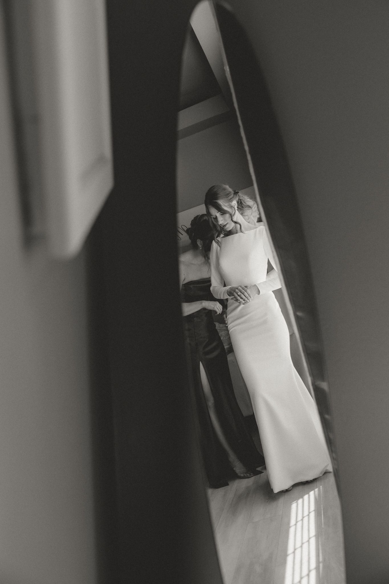 Artistic black and white mirror reflection of a couple in formal attire.