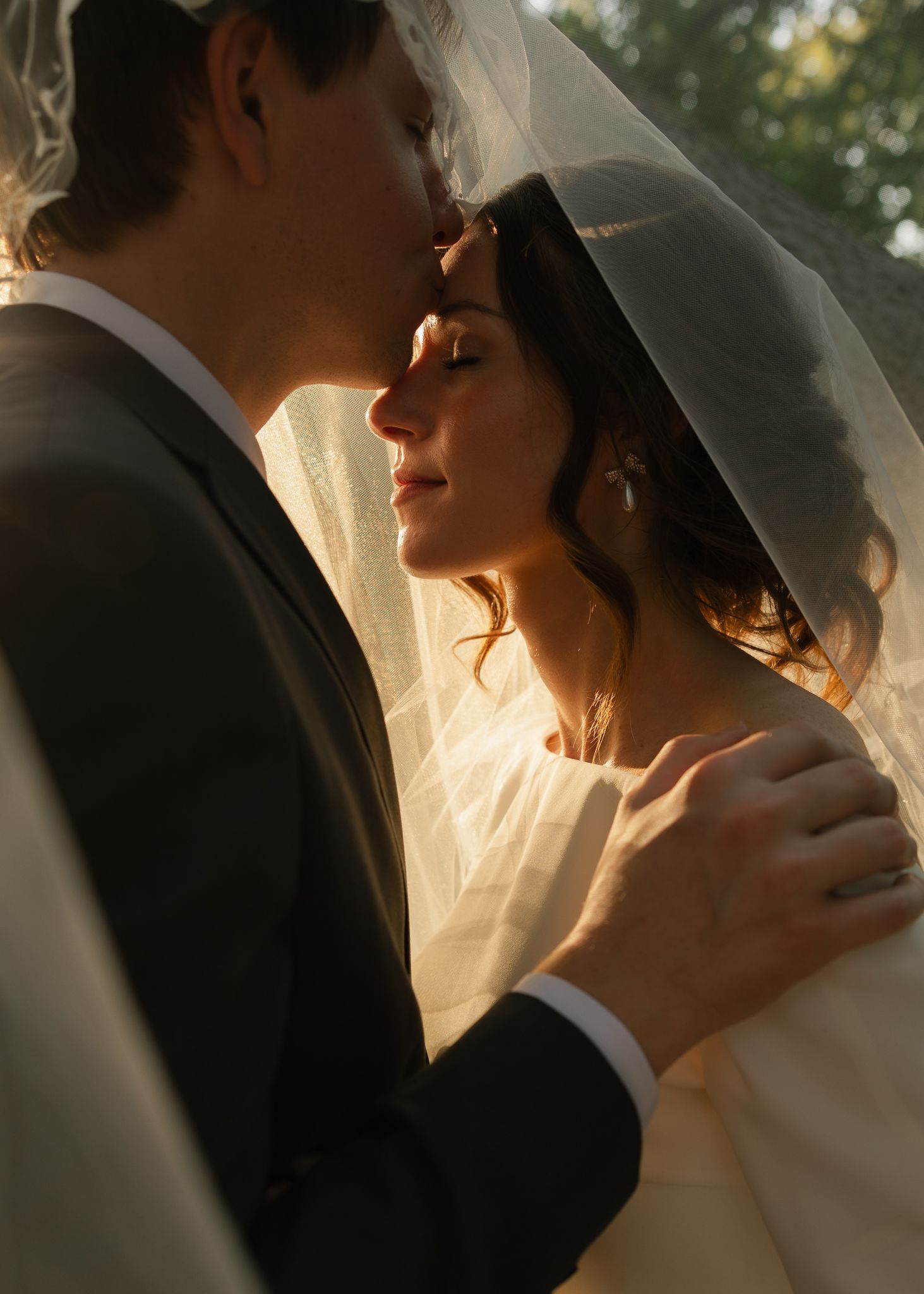 Golden hour wedding portrait with sunlight filtering through a bridal veil.