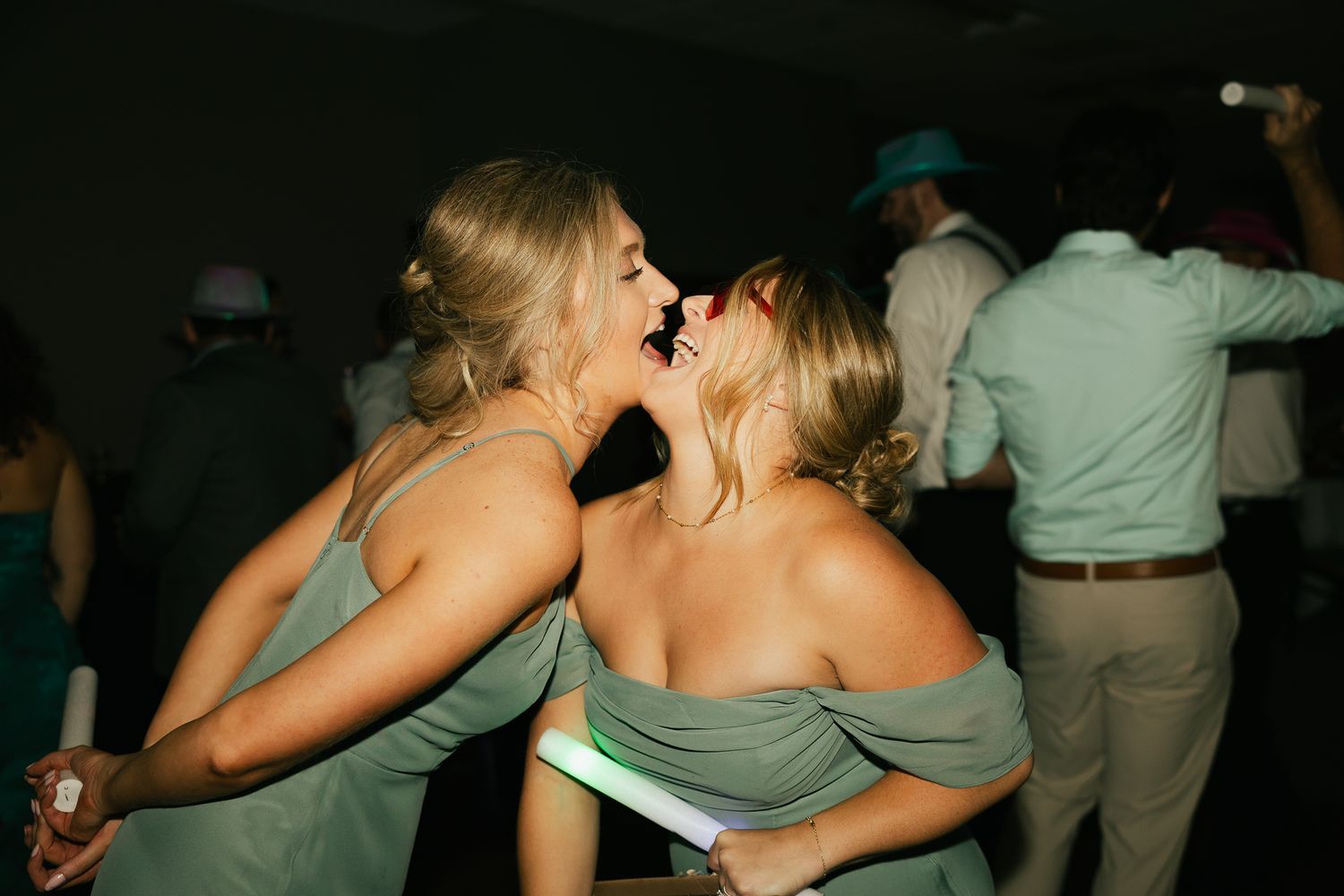 People embracing and dancing together at a dark indoor event.