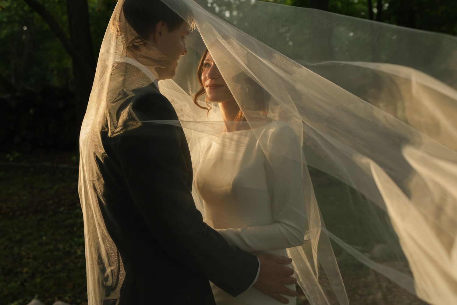 A flowing wedding veil catches the breeze in an artistic outdoor portrait.
