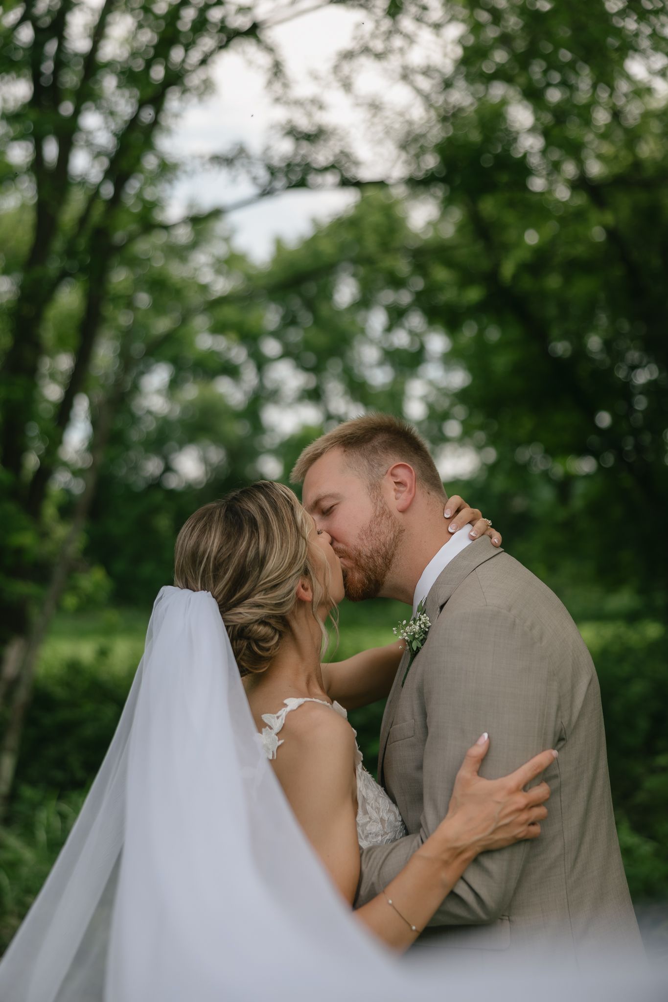 A tender moment between newlyweds sharing a kiss in a garden setting.