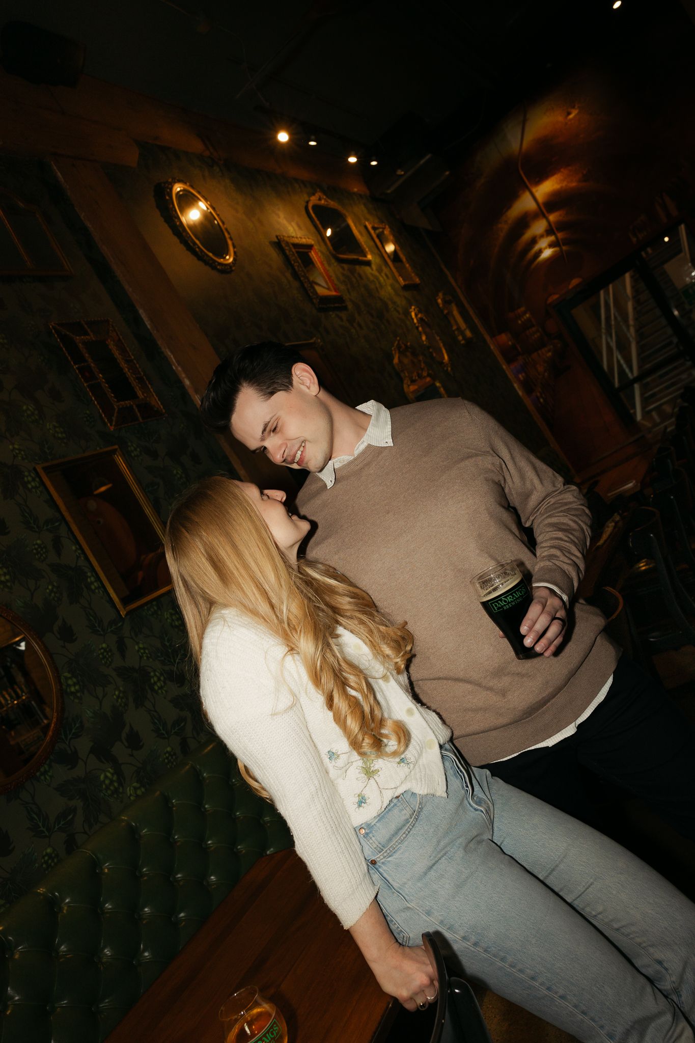 Cozy bar interior with dark wood paneling and couple sharing drinks.