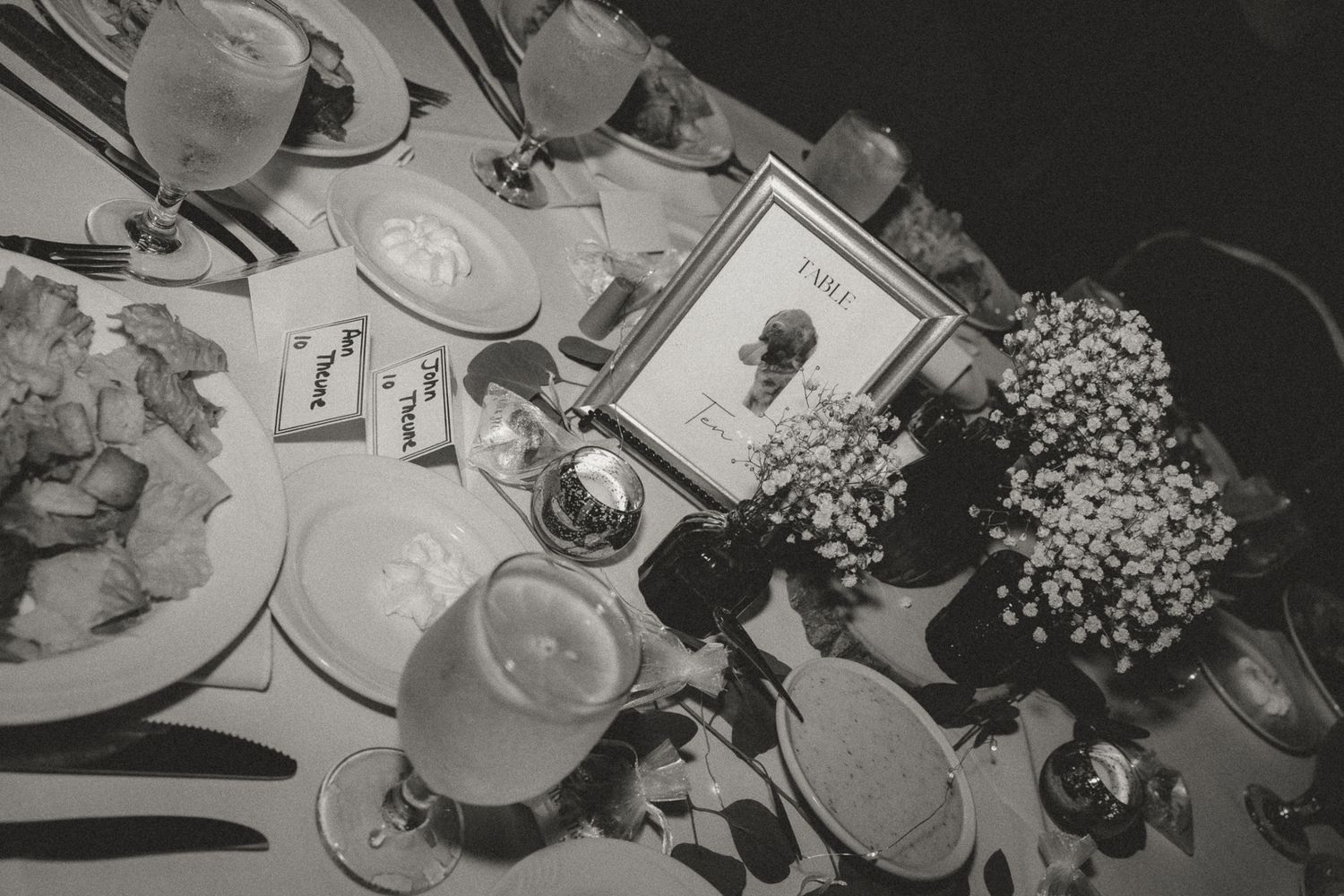 Black and white photo of elegant table settings at a wedding reception.