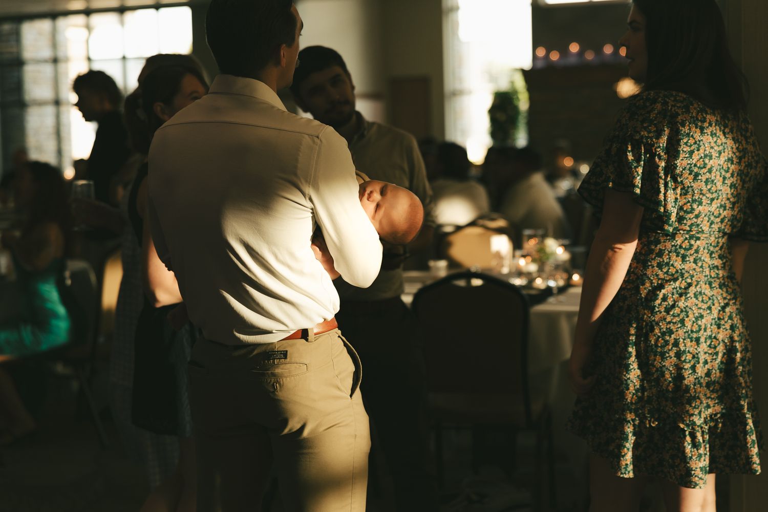 Silhouettes of wedding guests mingling in a warmly lit indoor venue.