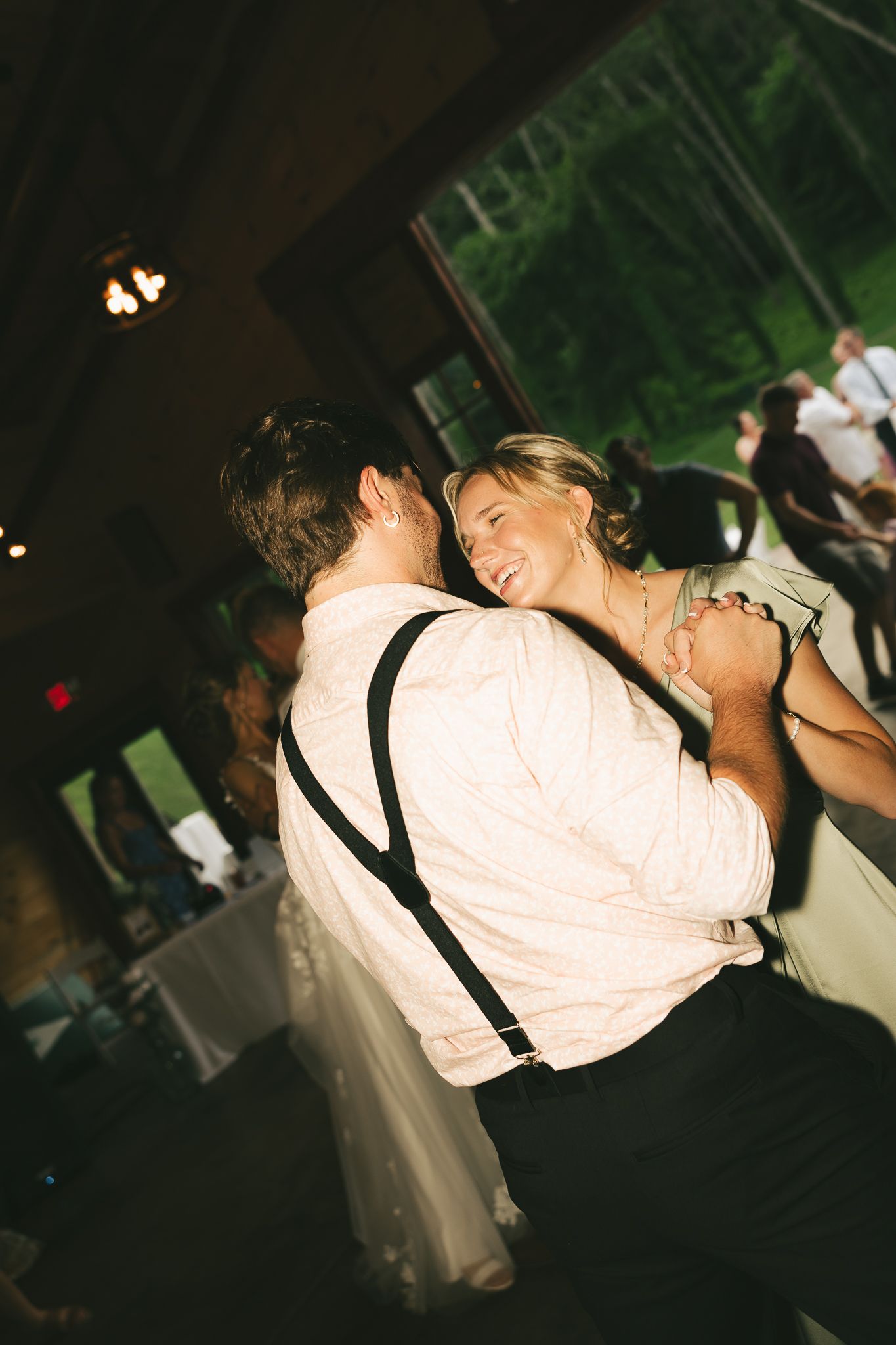Wedding guests dancing and celebrating at a dimly lit indoor reception.