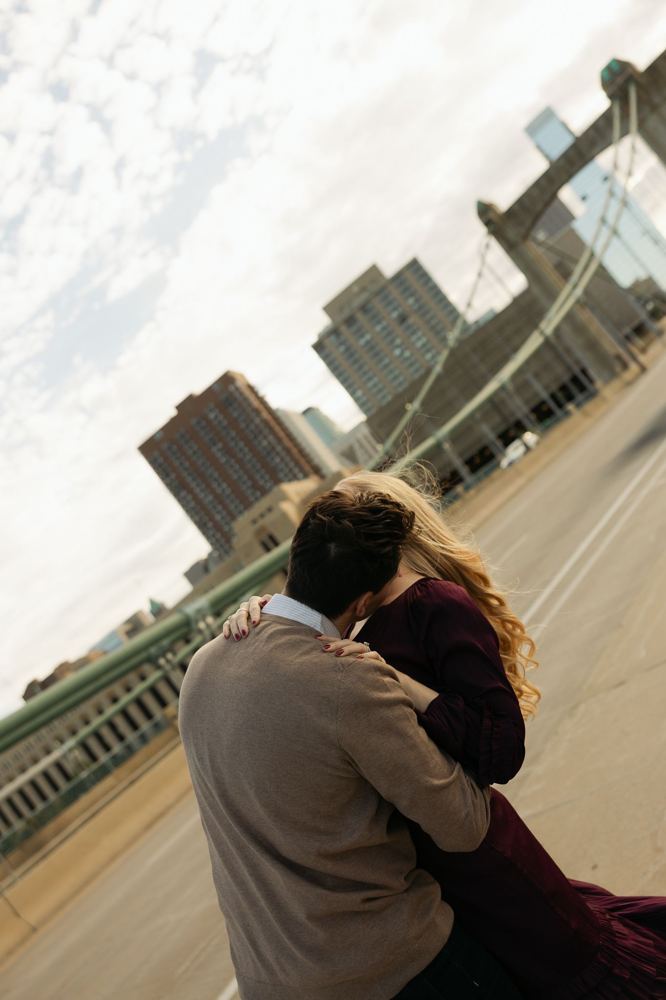 Urban cityscape view with couple embracing in foreground against downtown buildings.