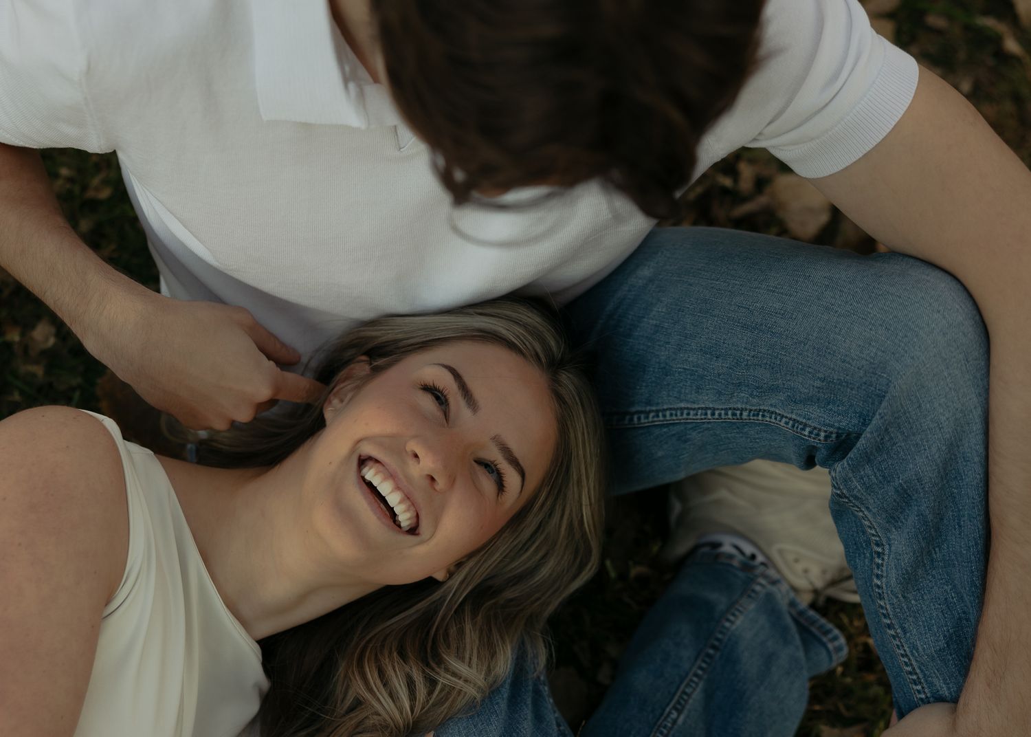Intimate couple's photoshoot showing affectionate moments while lying down outdoors.