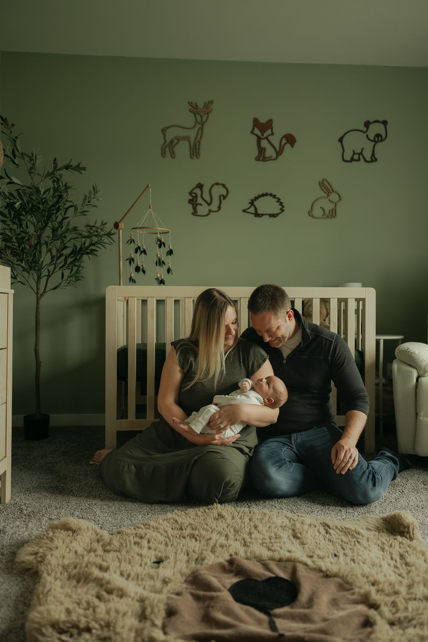 A family bonds together in a cozy nursery decorated with woodland animal wall decals.