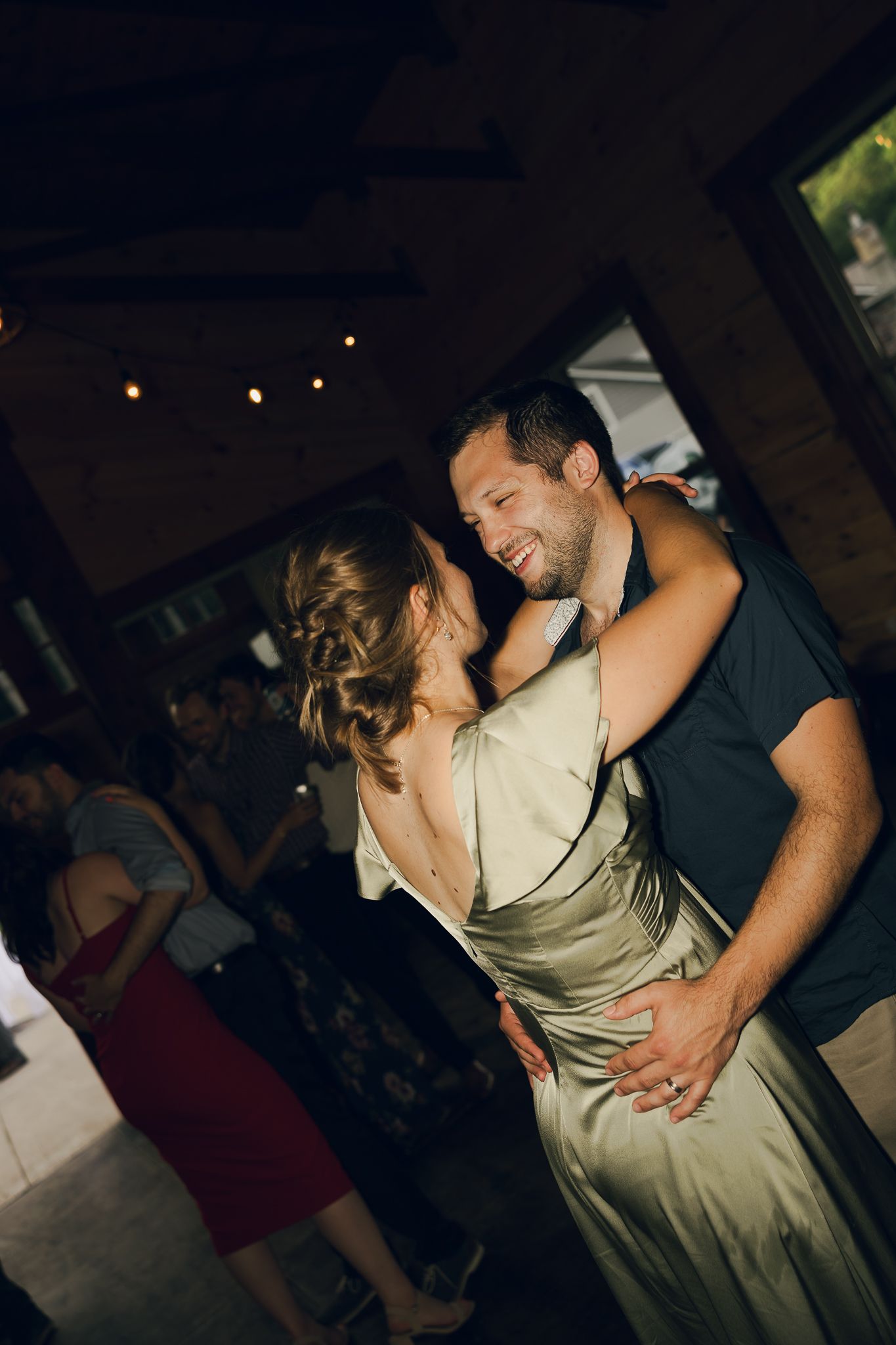 A couple shares an intimate dance moment at a wedding reception in a dimly lit venue.