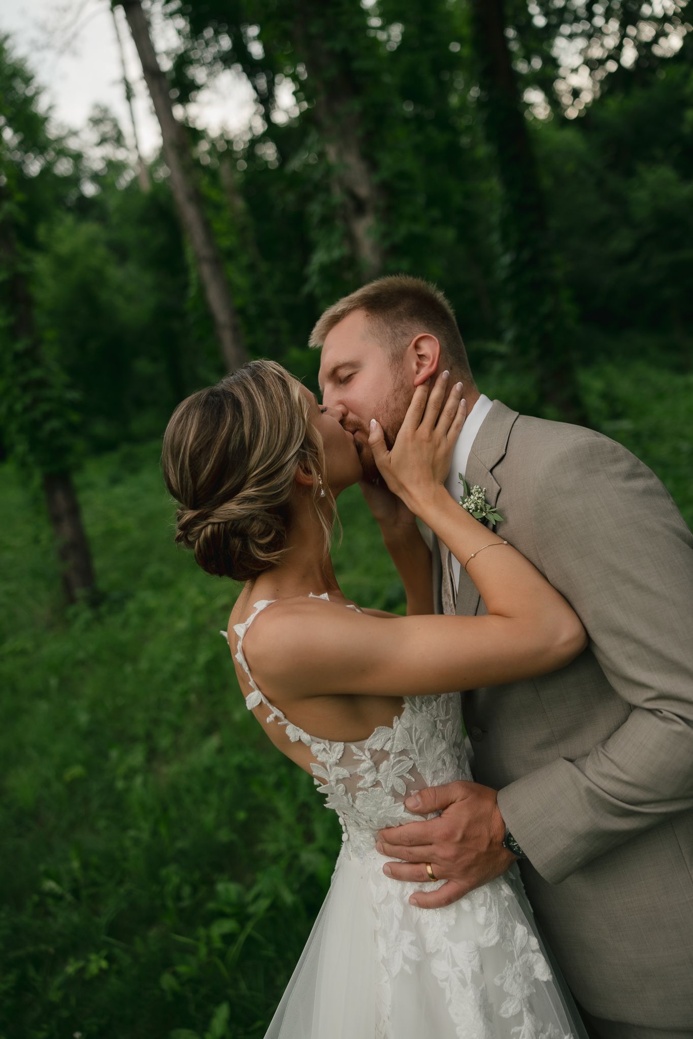 A tender wedding embrace photographed in a serene wooded setting at dusk.