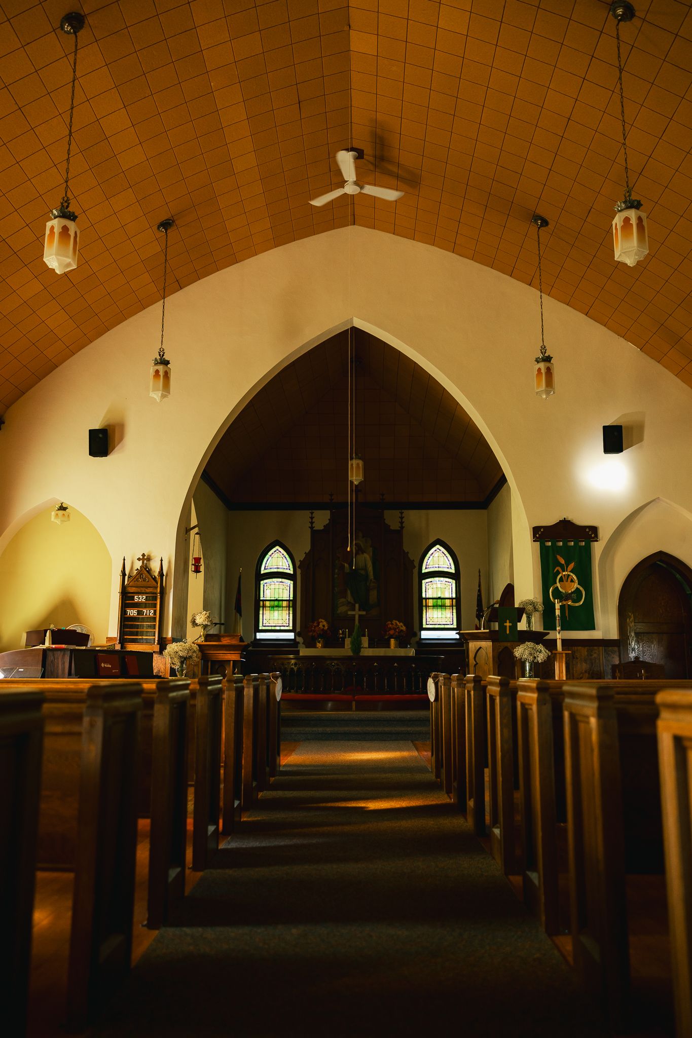 Interior of church sanctuary with arched ceiling and wooden pews illuminated by warm lighting.