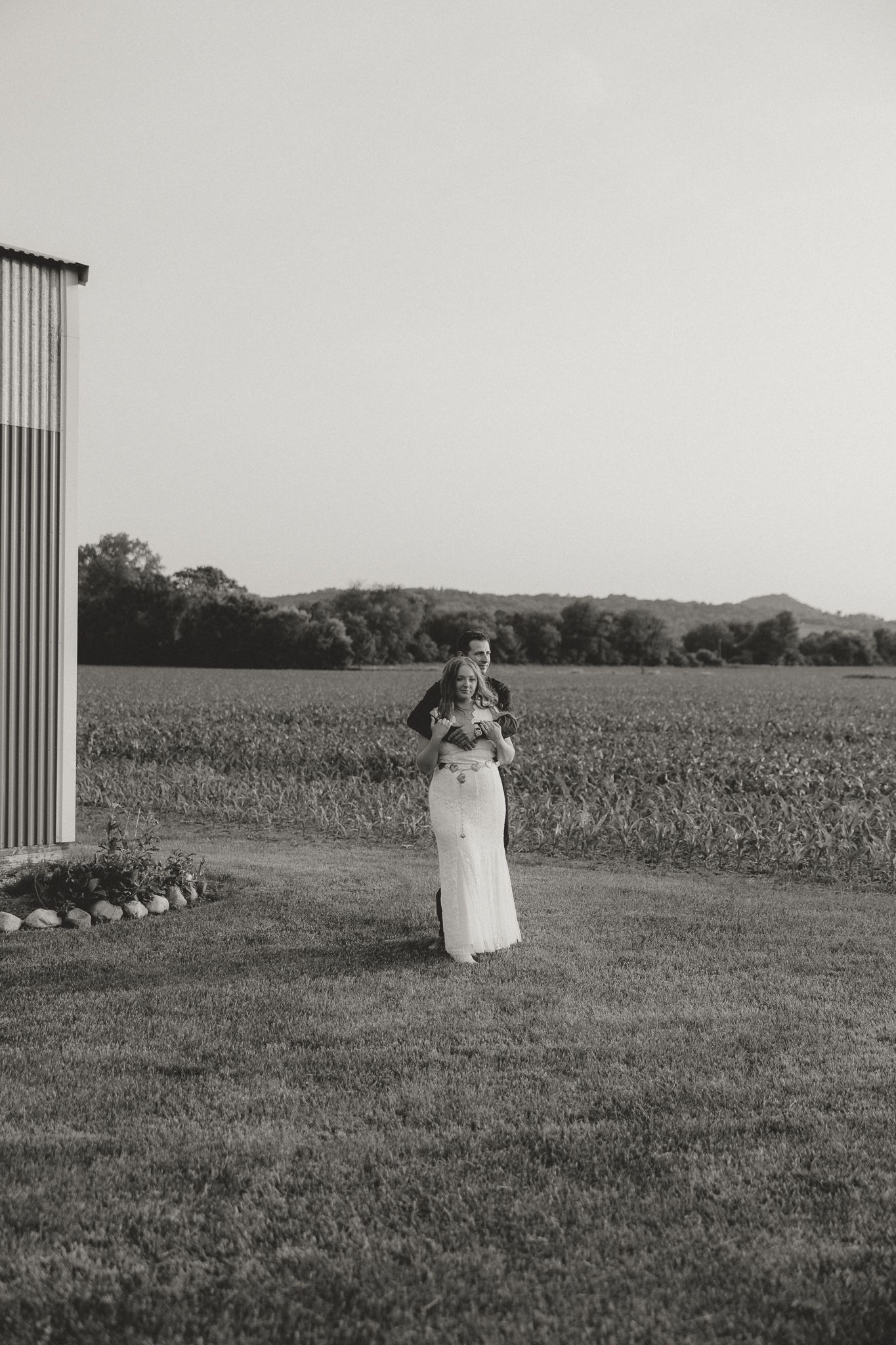 A wedding ceremony setup in a field with vertical decorative elements against an open landscape.