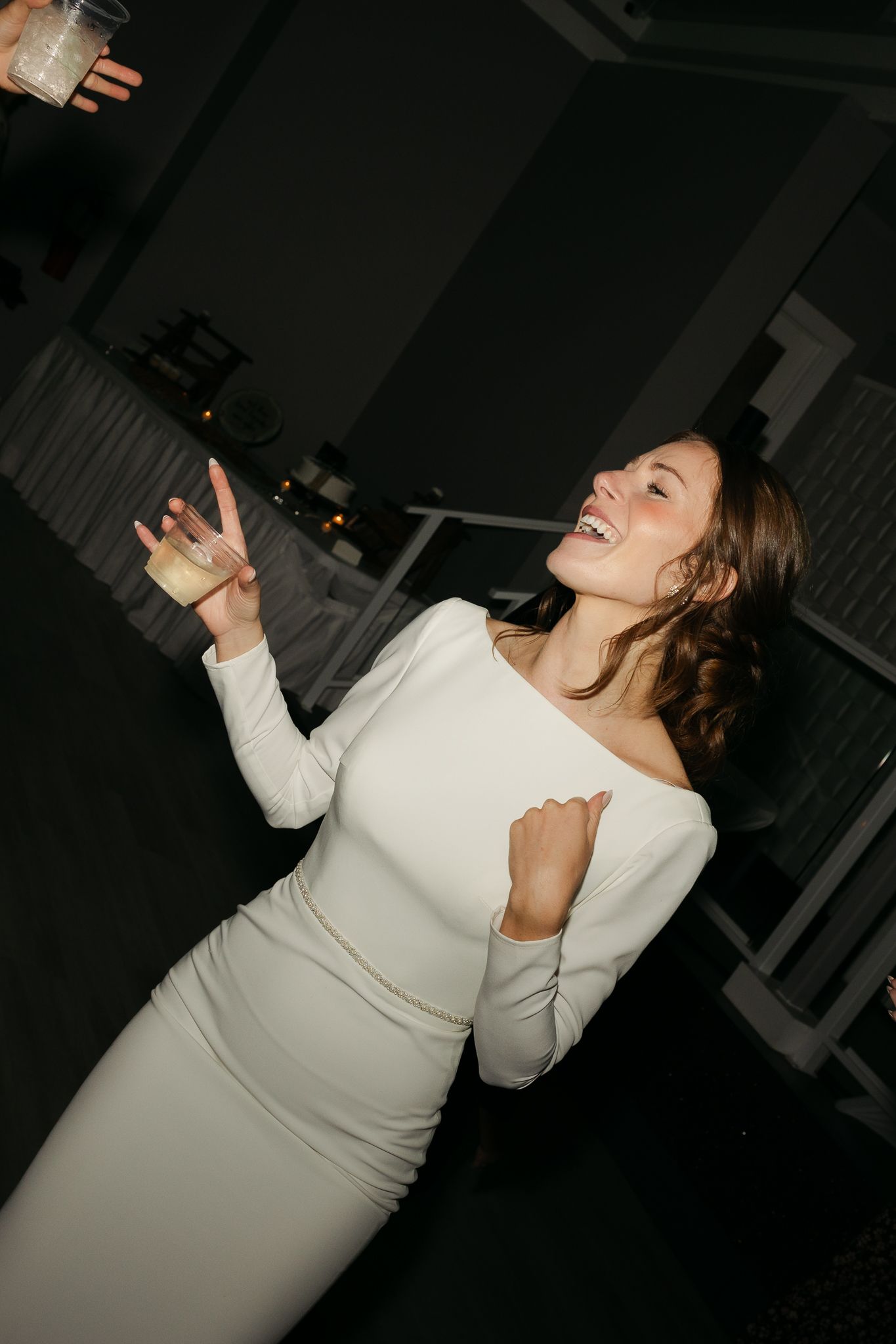 Woman in white form-fitting dress dancing joyfully at a celebration.
