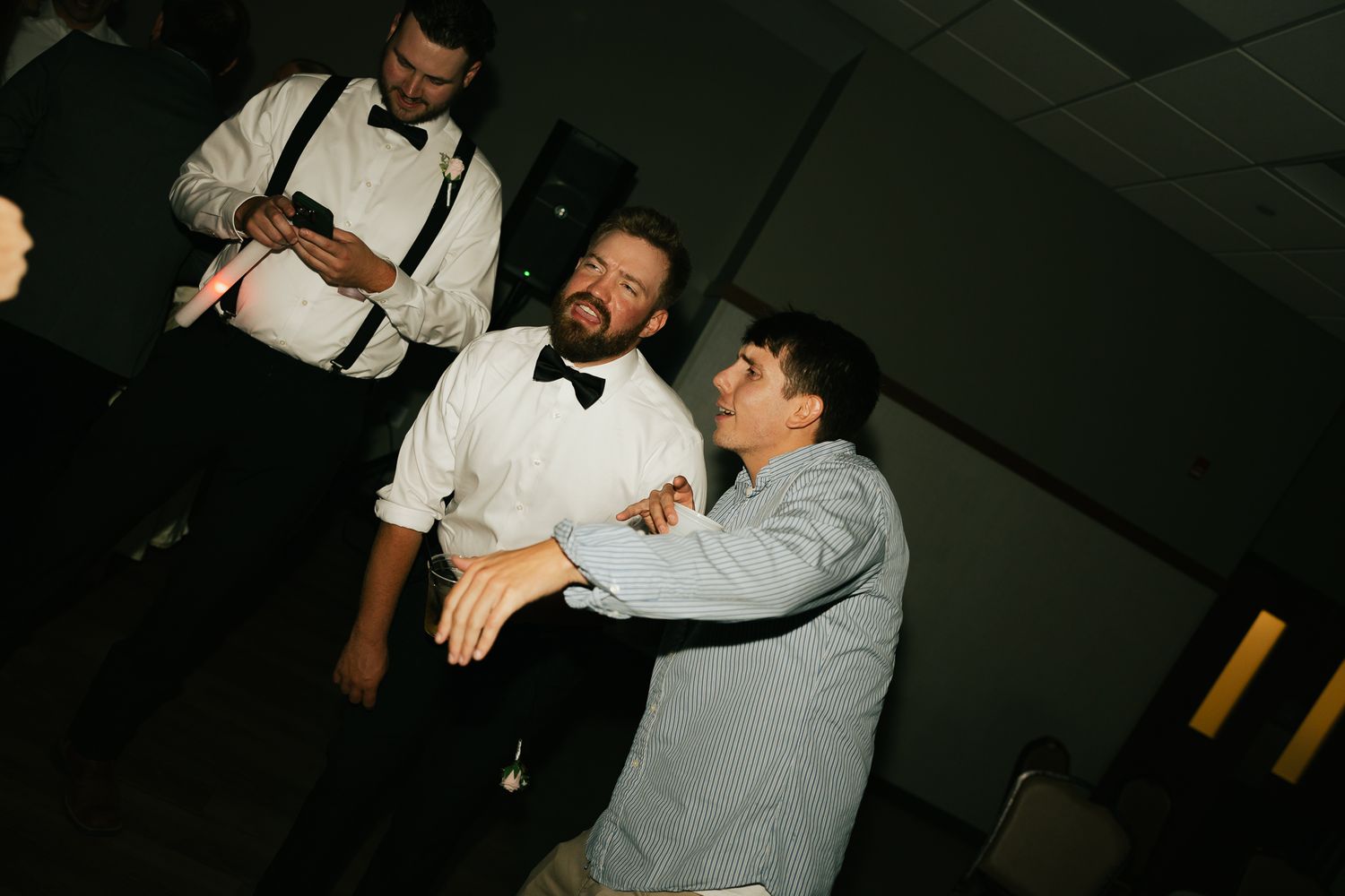 People dancing and having fun at a dimly lit reception party.